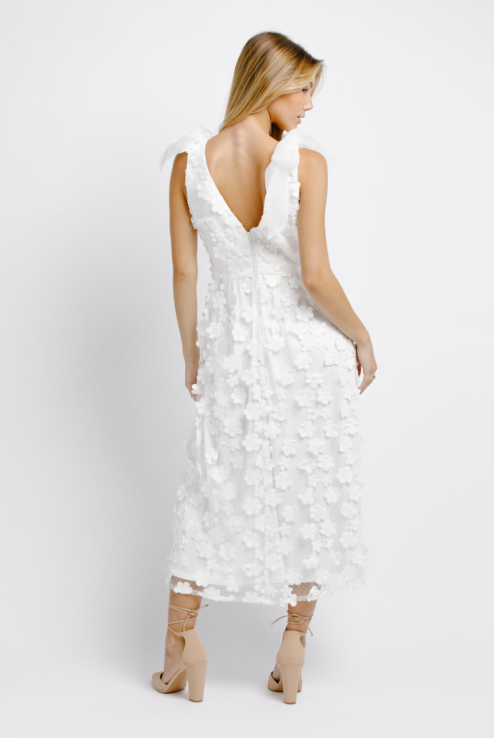 Back view of a woman wearing a white floral dress on a white background