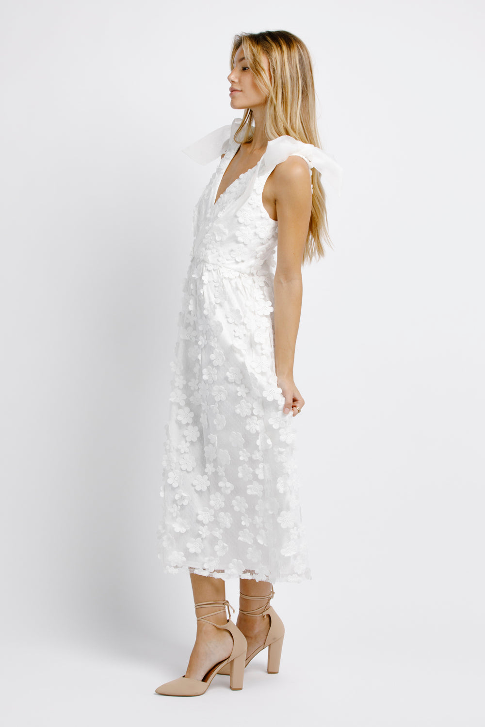 Side view of a woman wearing a white floral dress on a white background