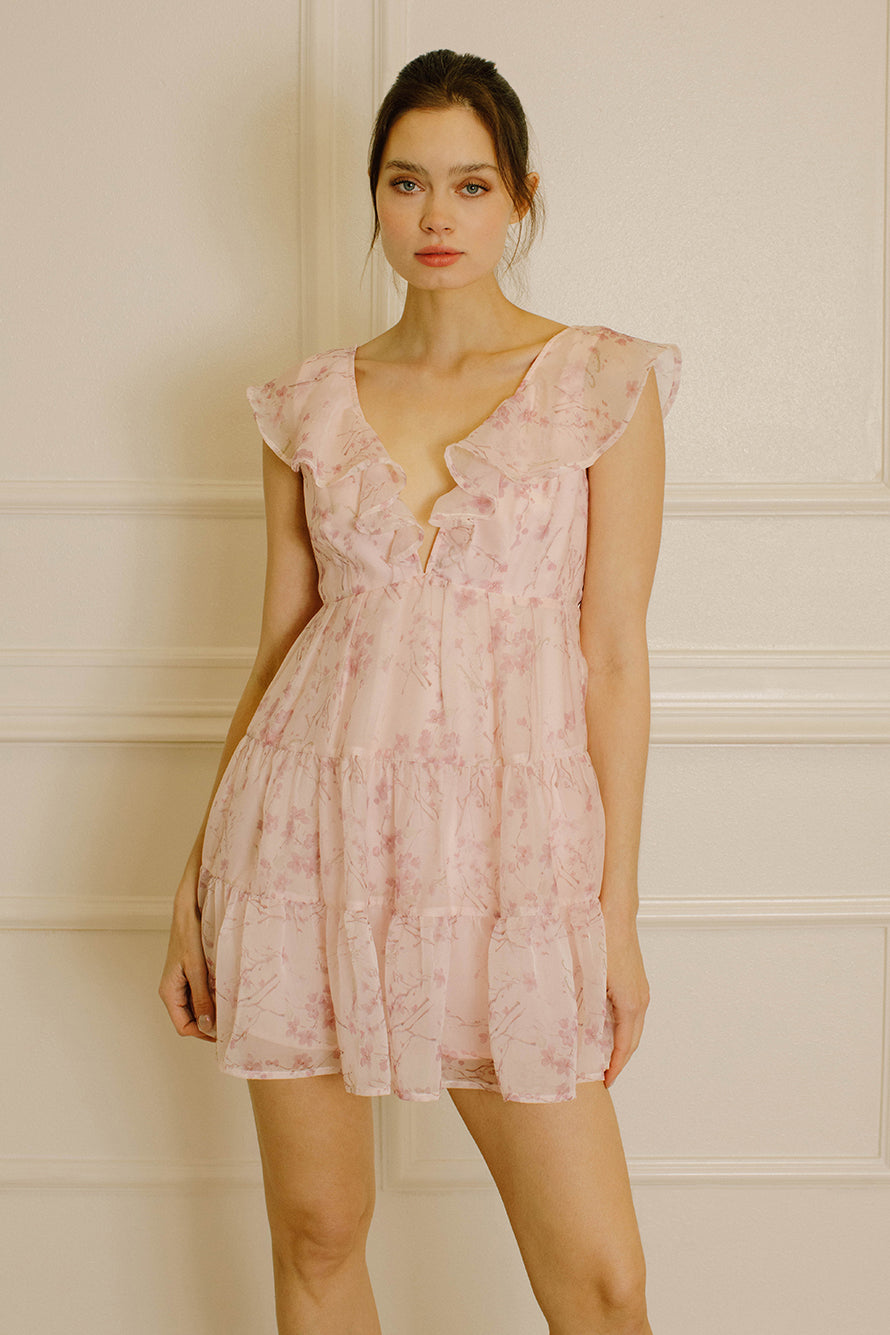 Woman wearing a pink dress with a cherry blossom print against a neutral background