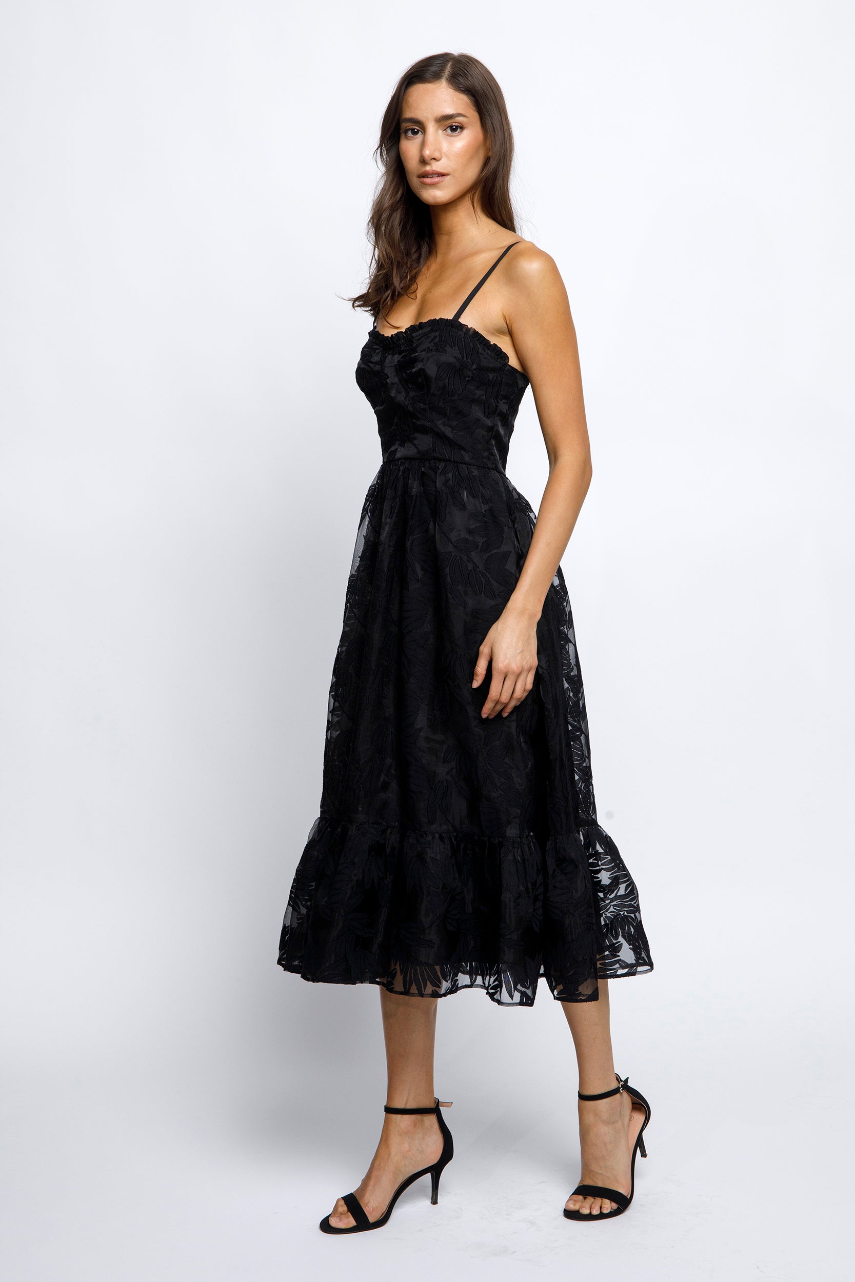 Woman wearing a black lace midi dress on a white background