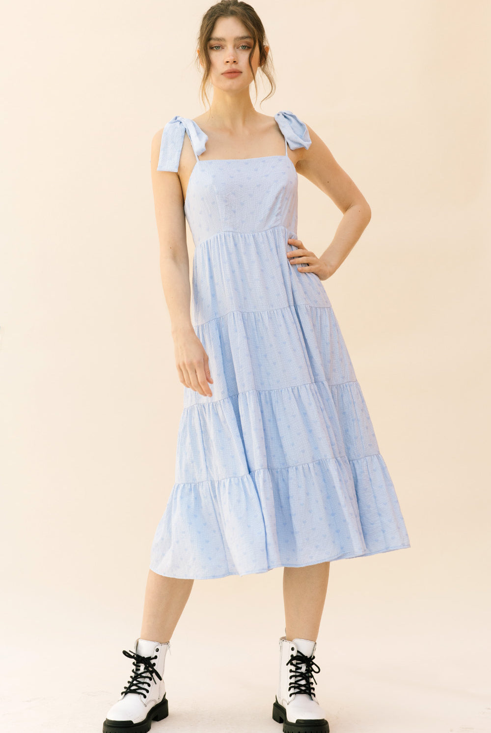Woman wearing a light blue dress with ruffled sleeves on a beige background