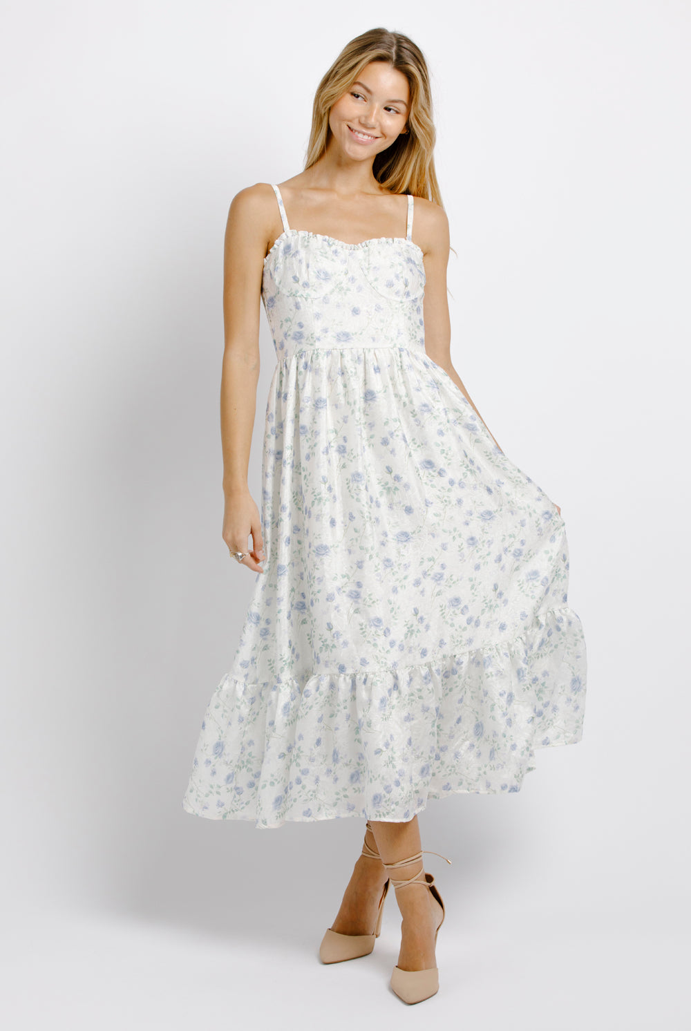 Woman wearing a white and blue floral dress on a plain background