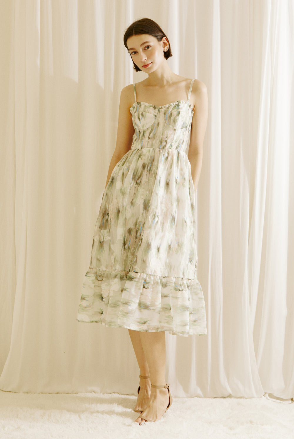 Woman wearing a green and blue tie dye effect dress standing against a plain background