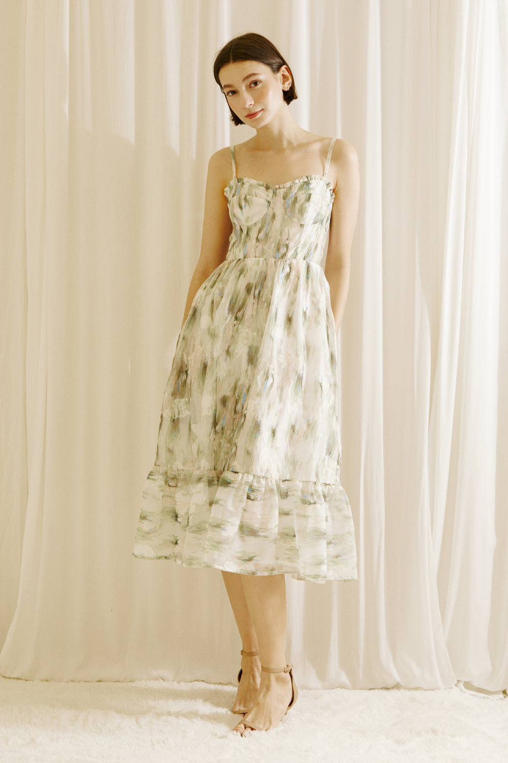 Woman wearing a green and blue tie dye effect dress standing against a plain background