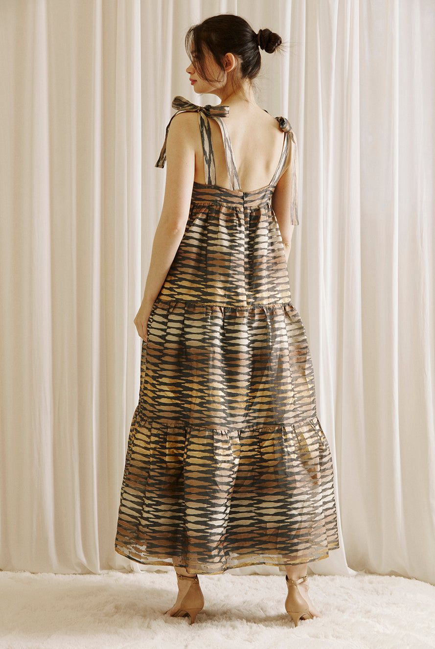 Back view of a woman wearing a boho maxi dress with striped pattern, featuring an empire waist, and self-tie straps.