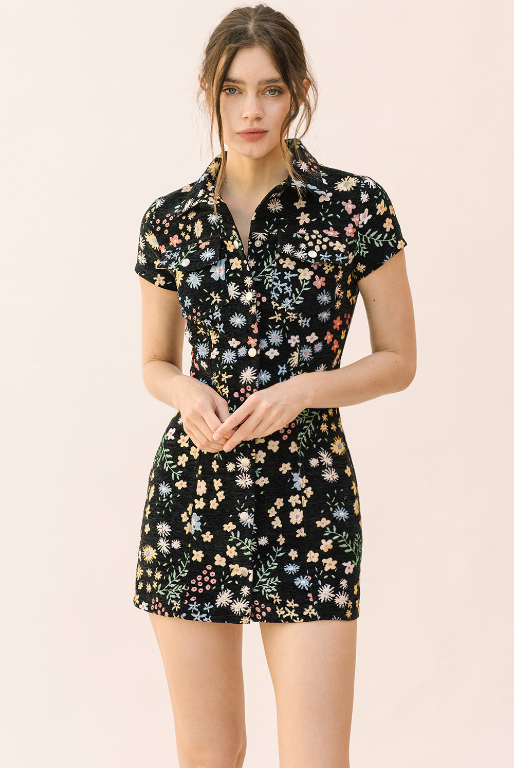 Woman wearing a black bodycon dress with floral pattern on a beige background