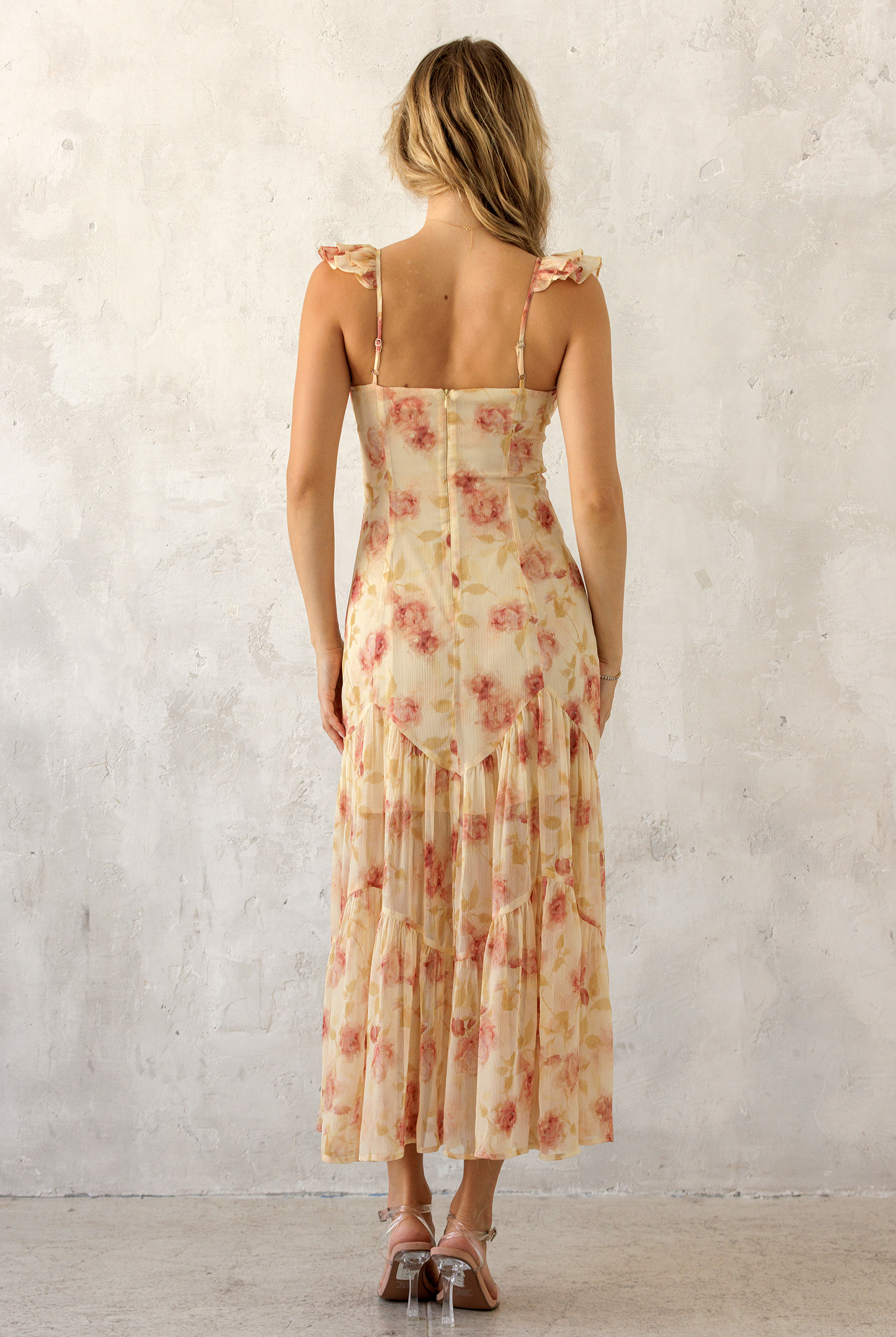A woman viewed from behind wearing a floral dress with a plain background