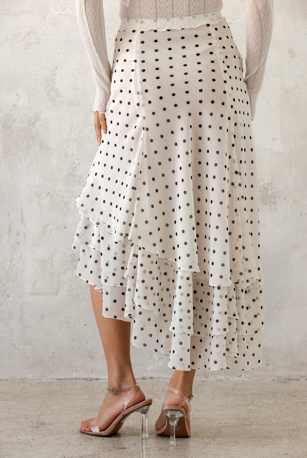 Person wearing a polka dot skirt with a plain background