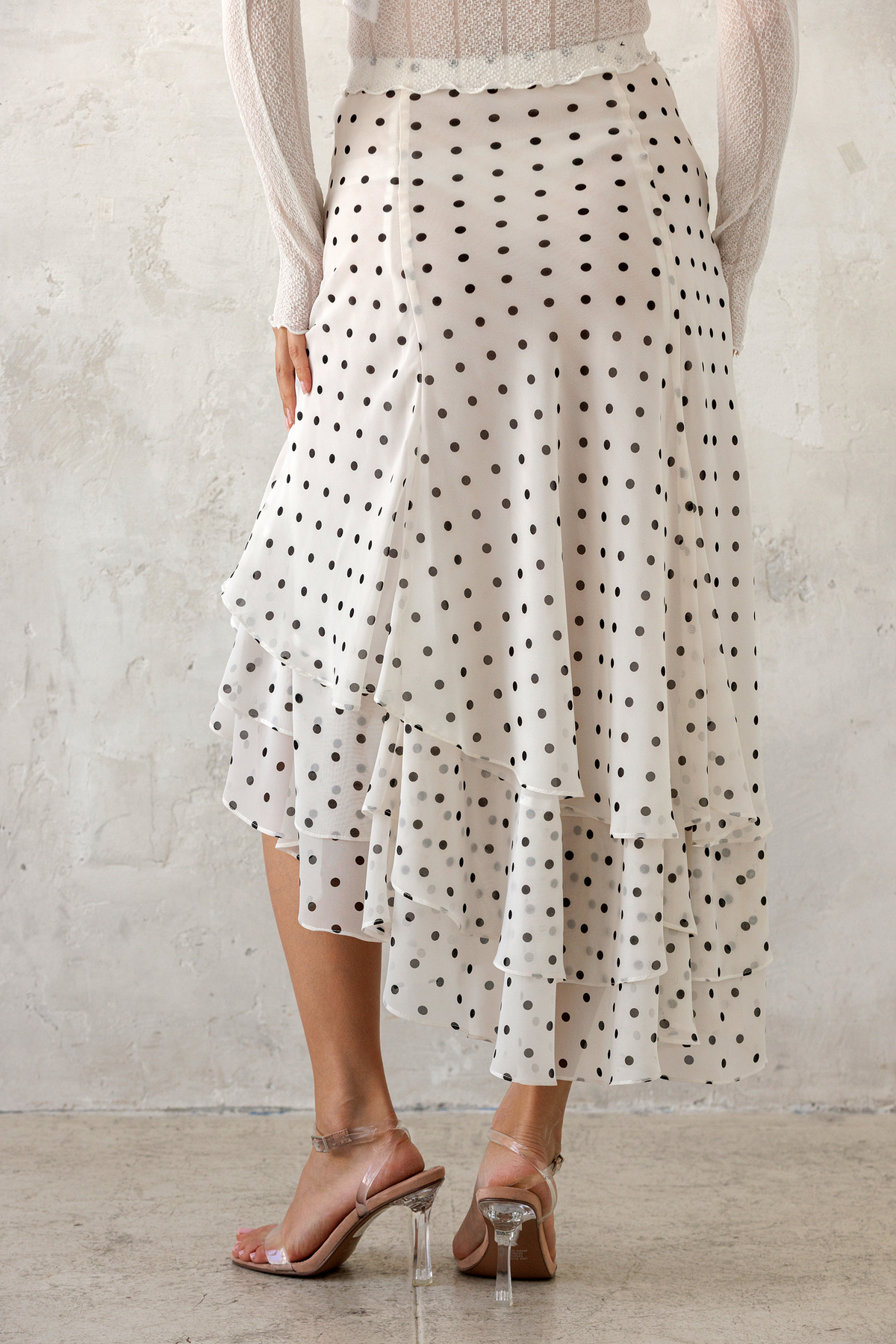 Person wearing a polka dot skirt with a plain background