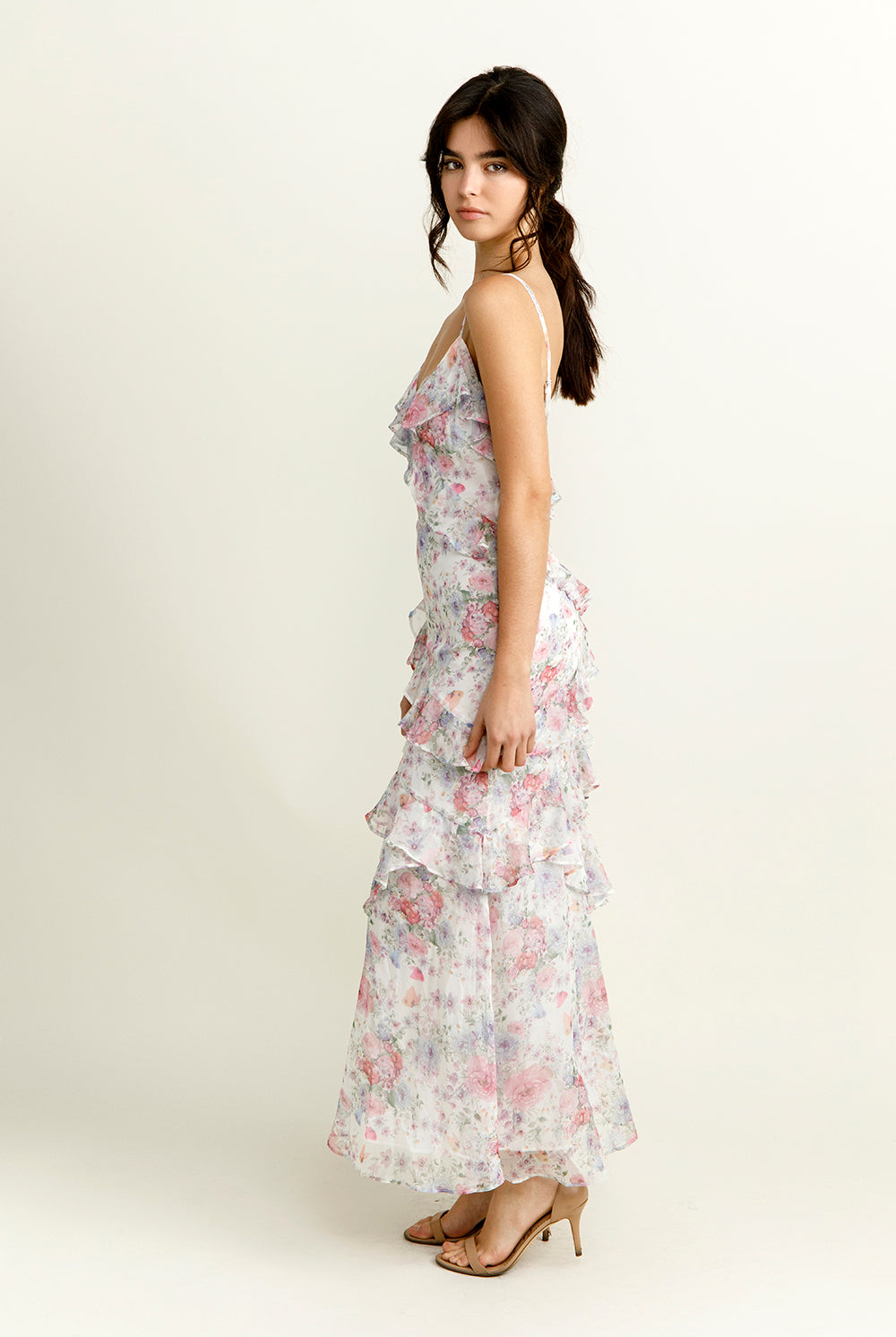 Side view of a woman wearing a purple floral dress on a white background
