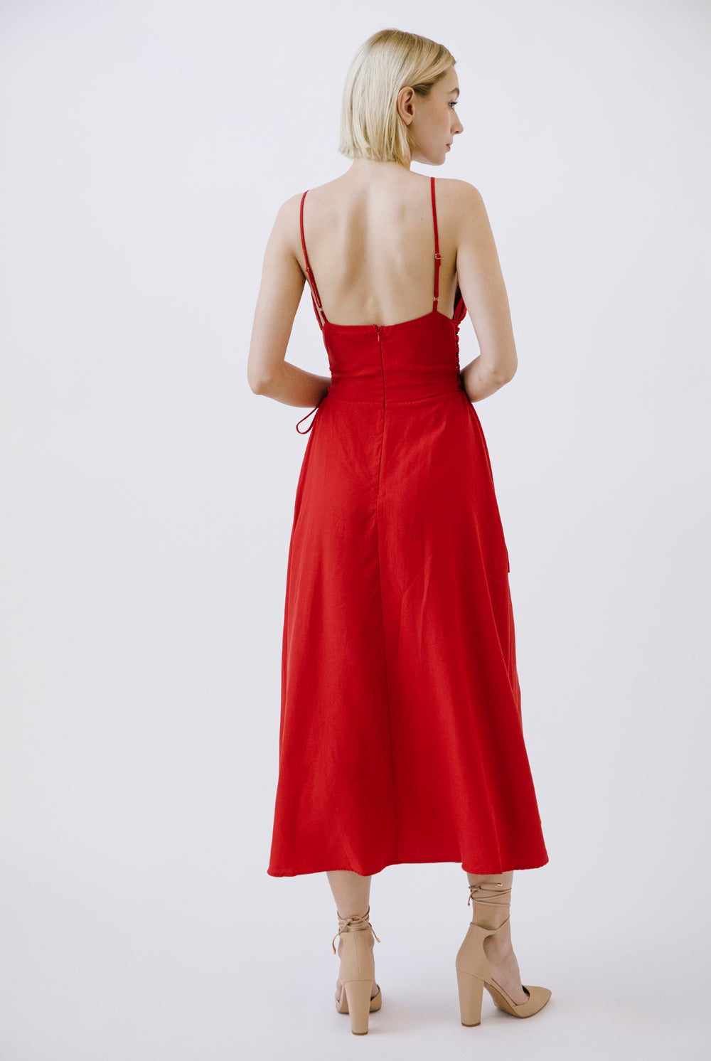 Woman wearing a red midi dress with thin straps on a white background