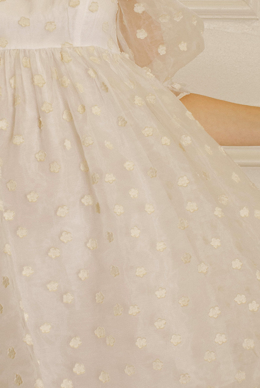 Cream polka dot dress against a neutral wall