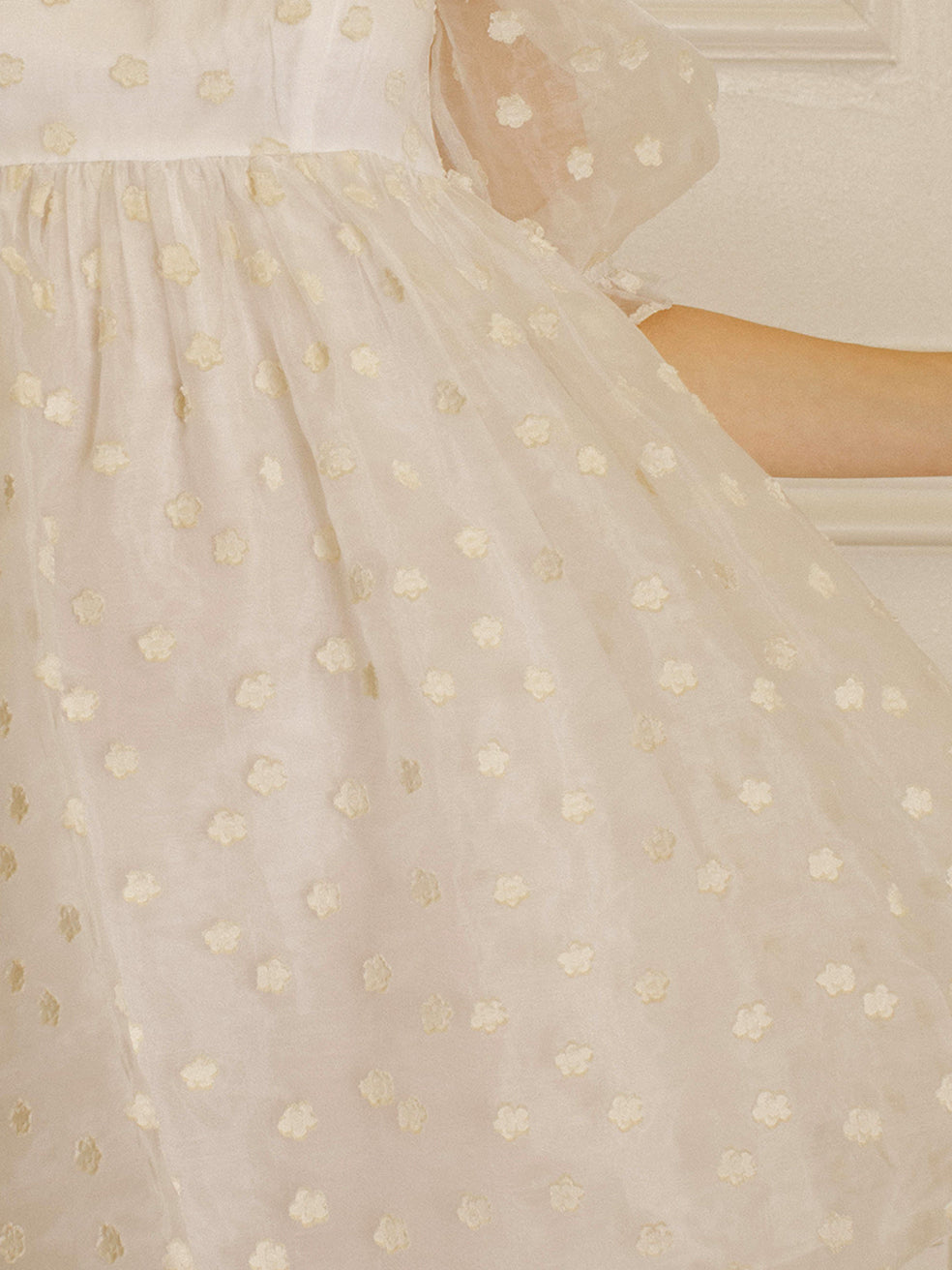 Cream polka dot dress against a neutral wall