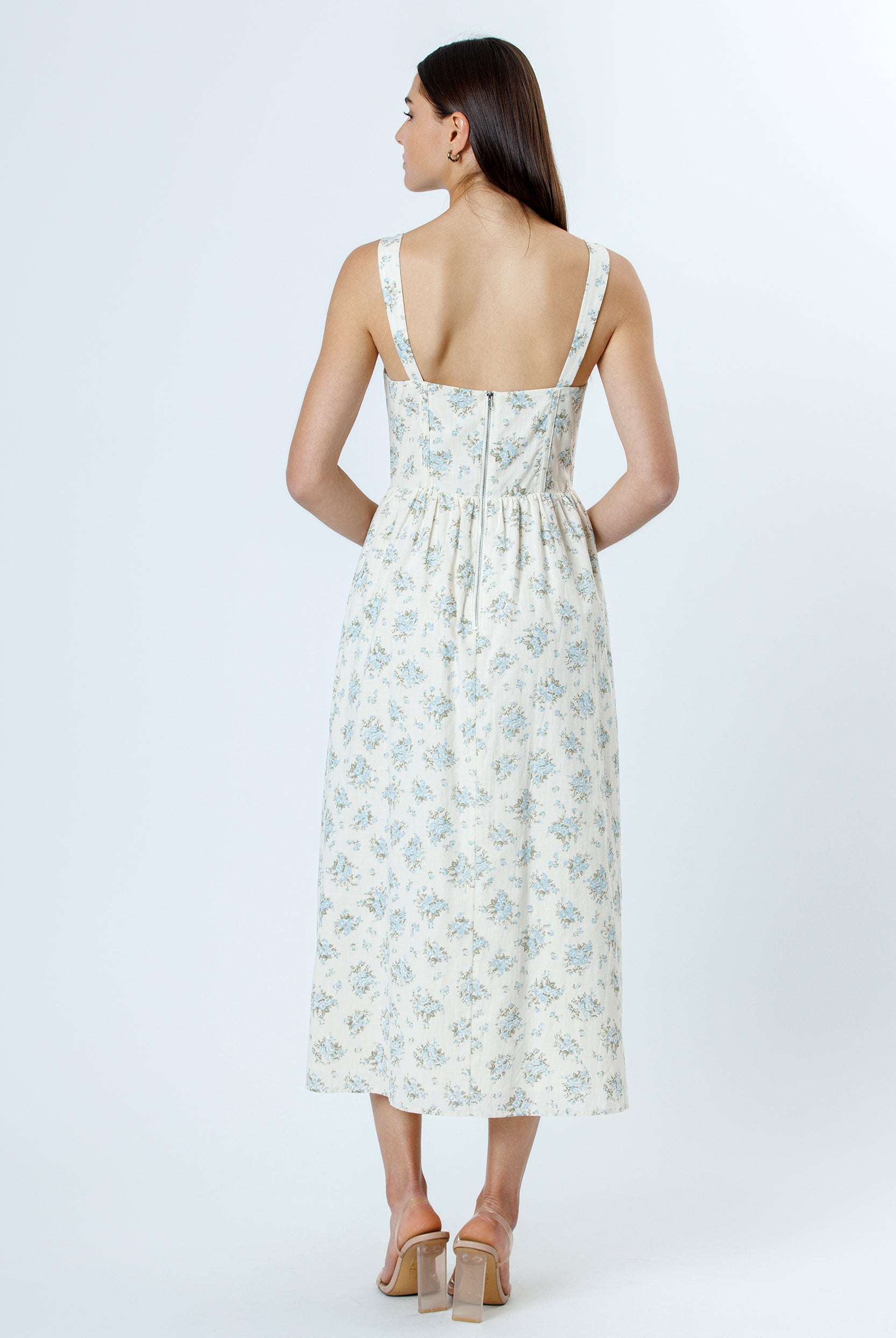 Back view of a woman wearing a floral dress on a white background