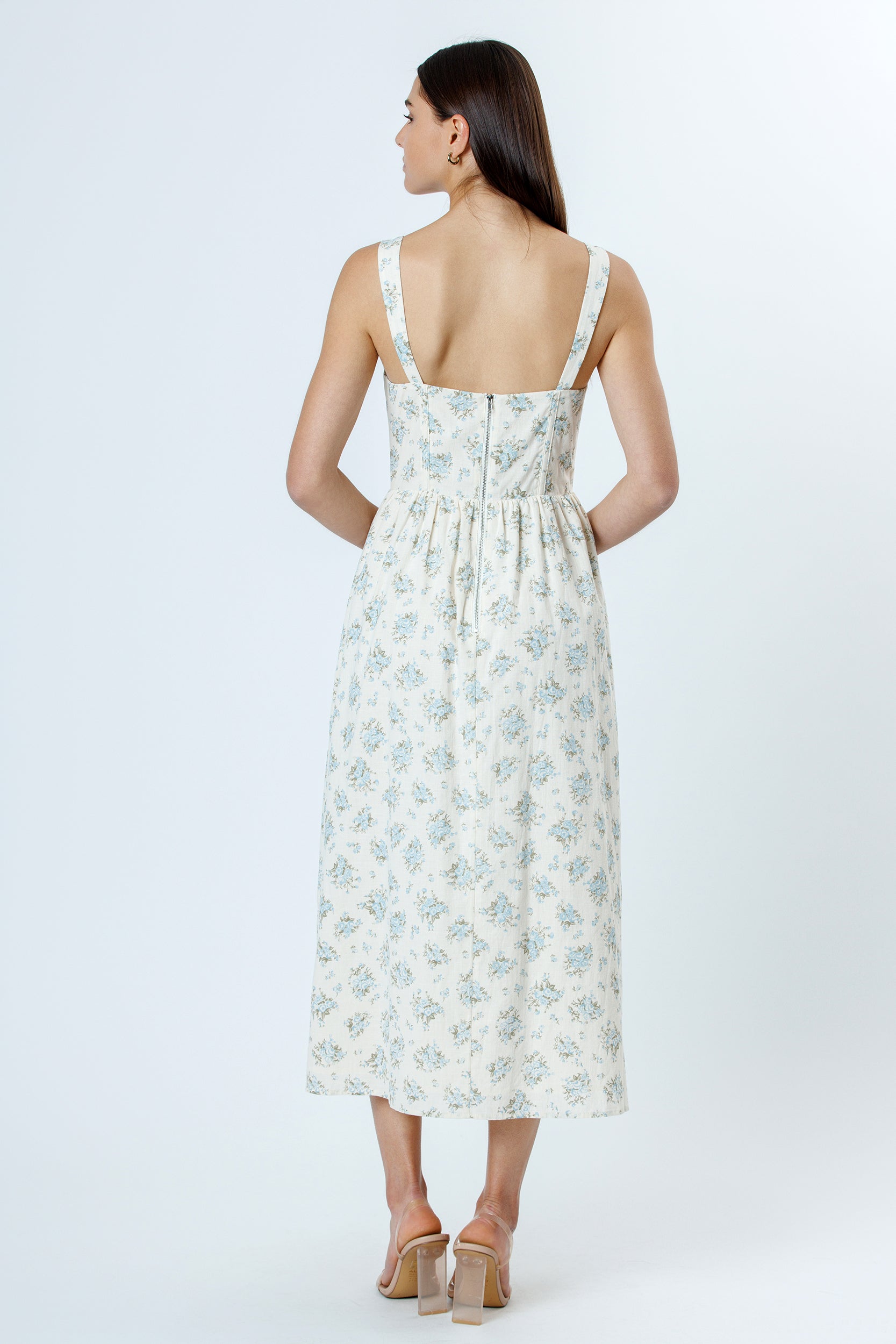 Back view of a woman wearing a floral dress on a white background