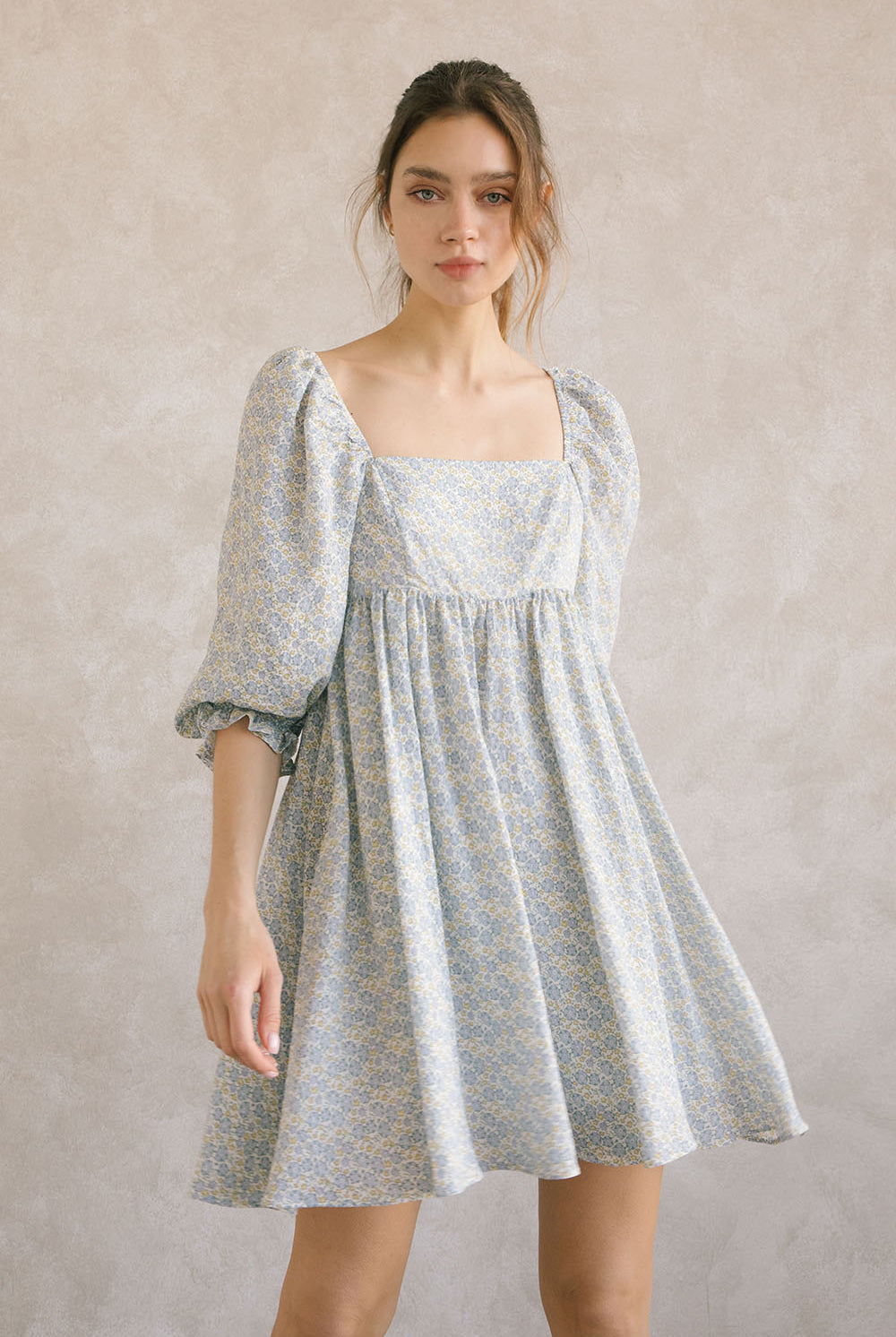 Woman wearing a blue floral dress against a plain background