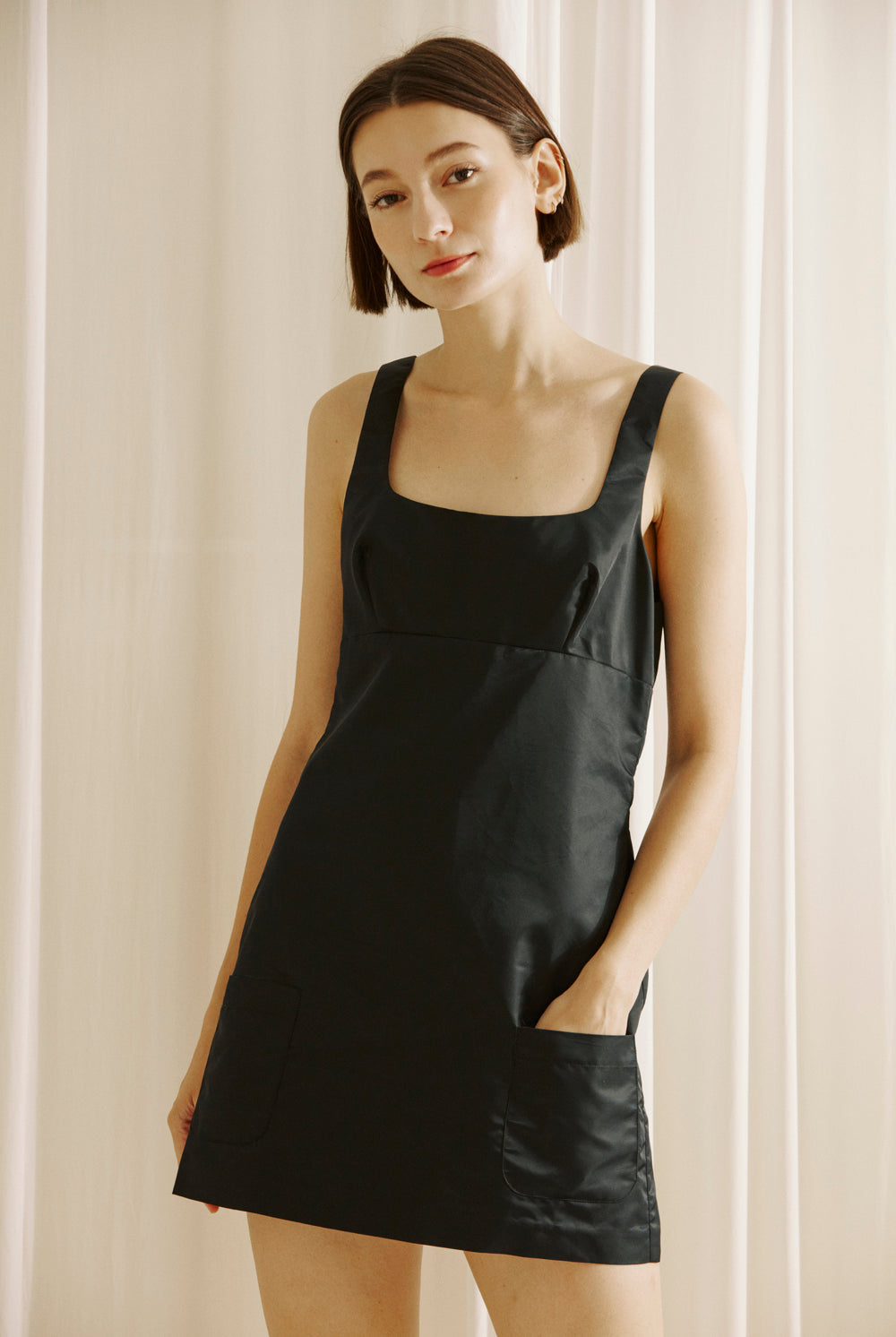 Woman wearing a black dress against a light background