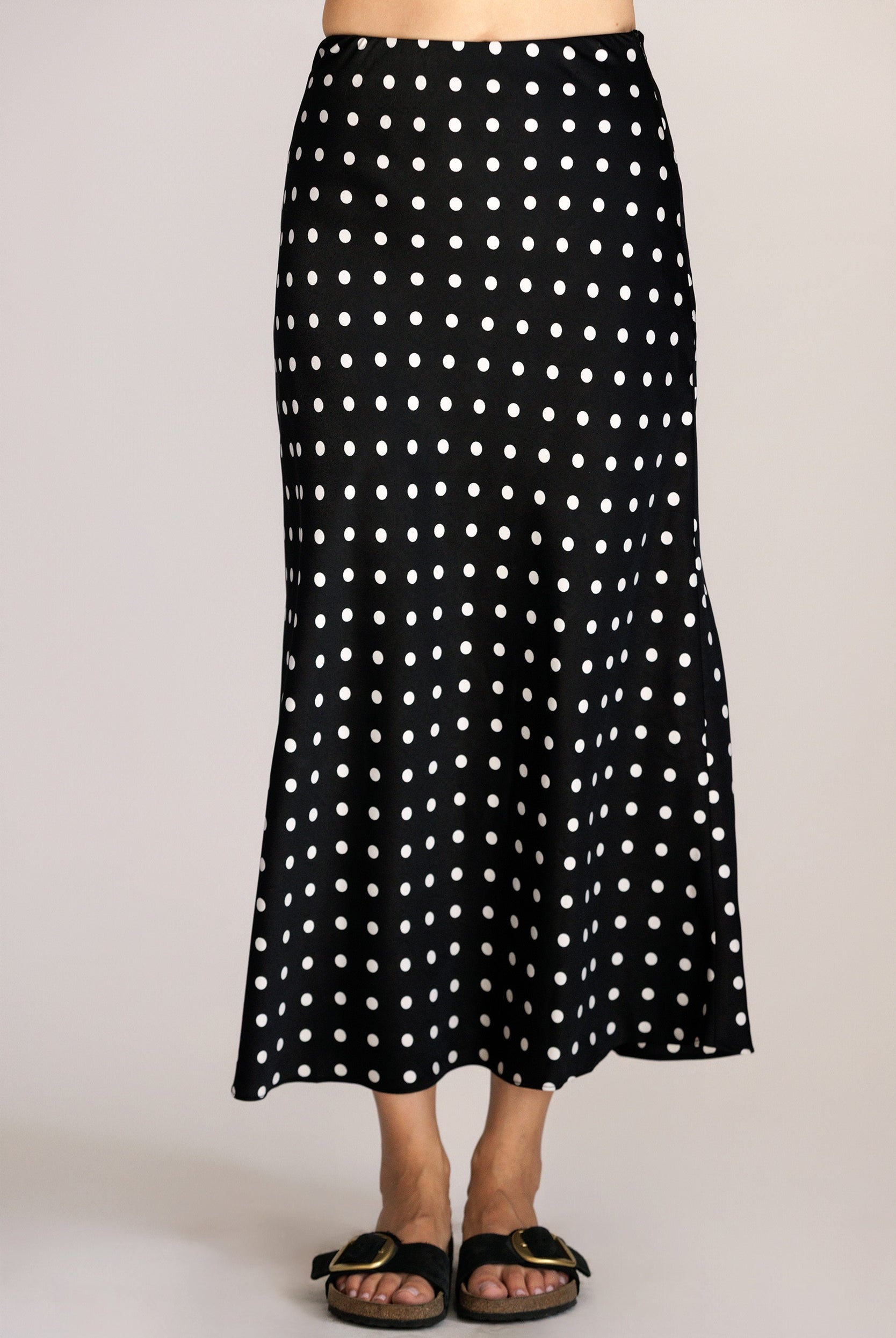 Black polka dot skirt worn by a person on a plain background