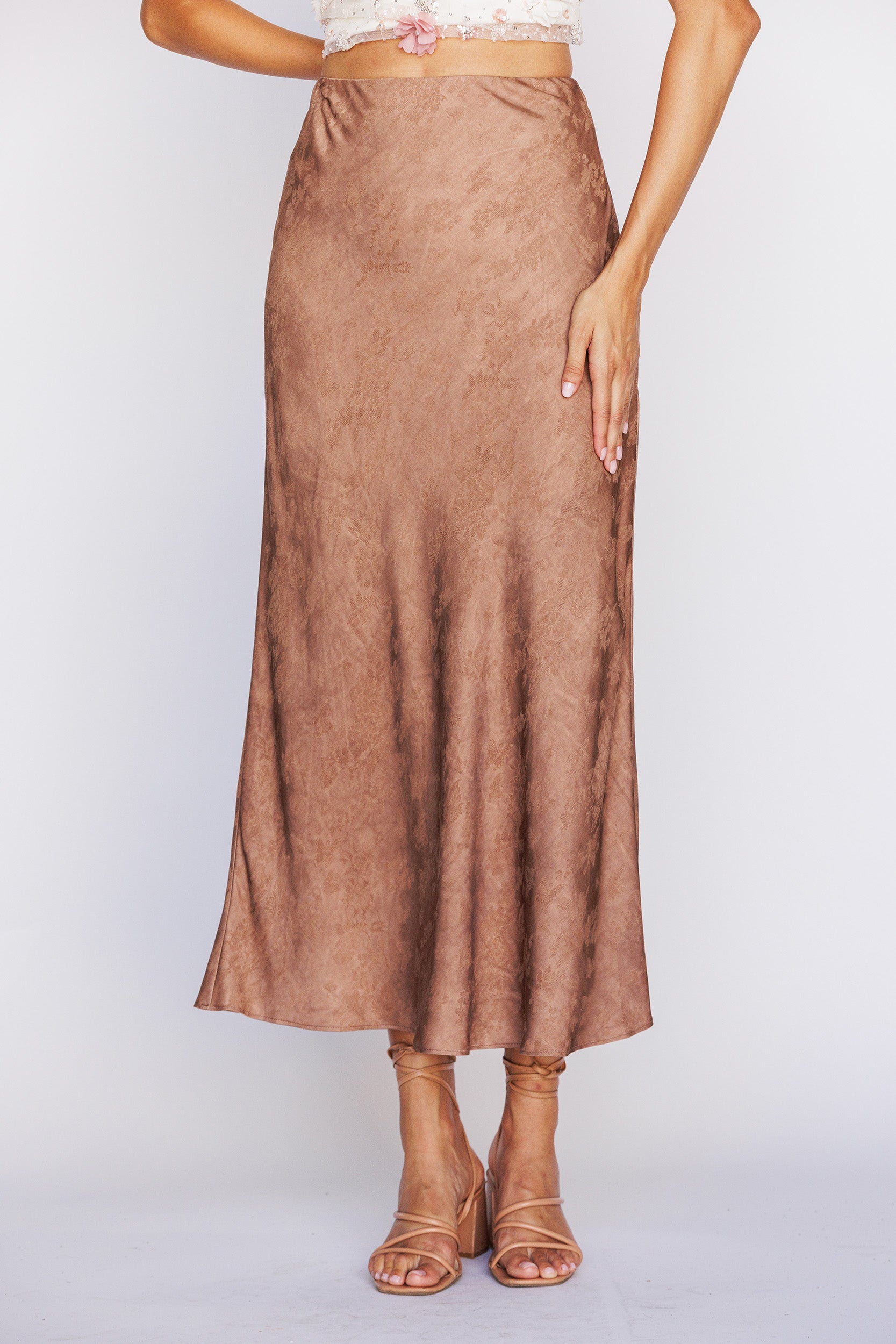 Brown satin-like skirt worn by a person on a white background