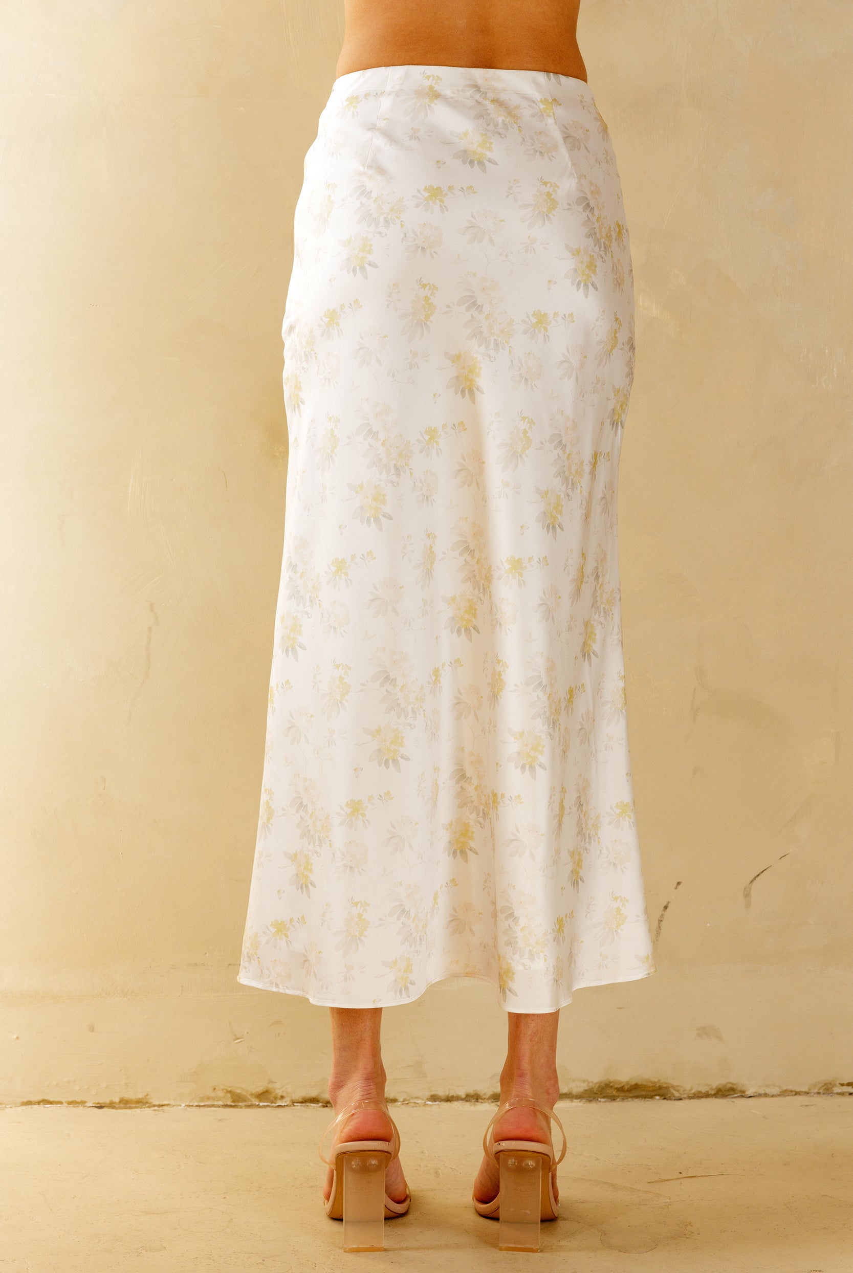 White floral skirt worn by a person on a beige background