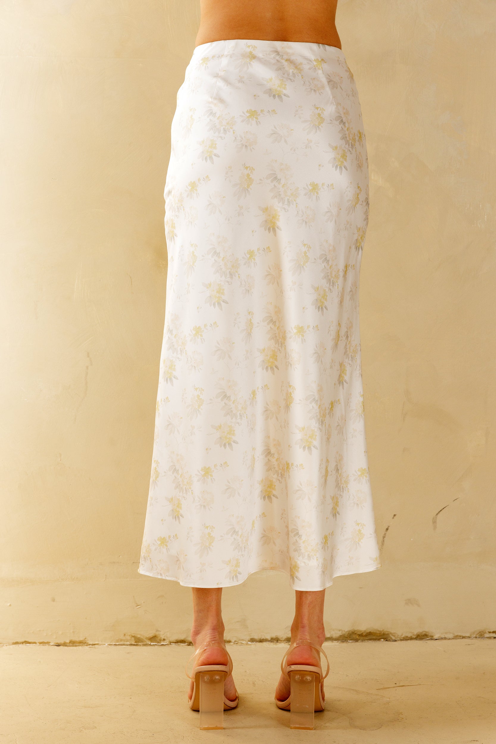 White floral skirt worn by a person on a beige background