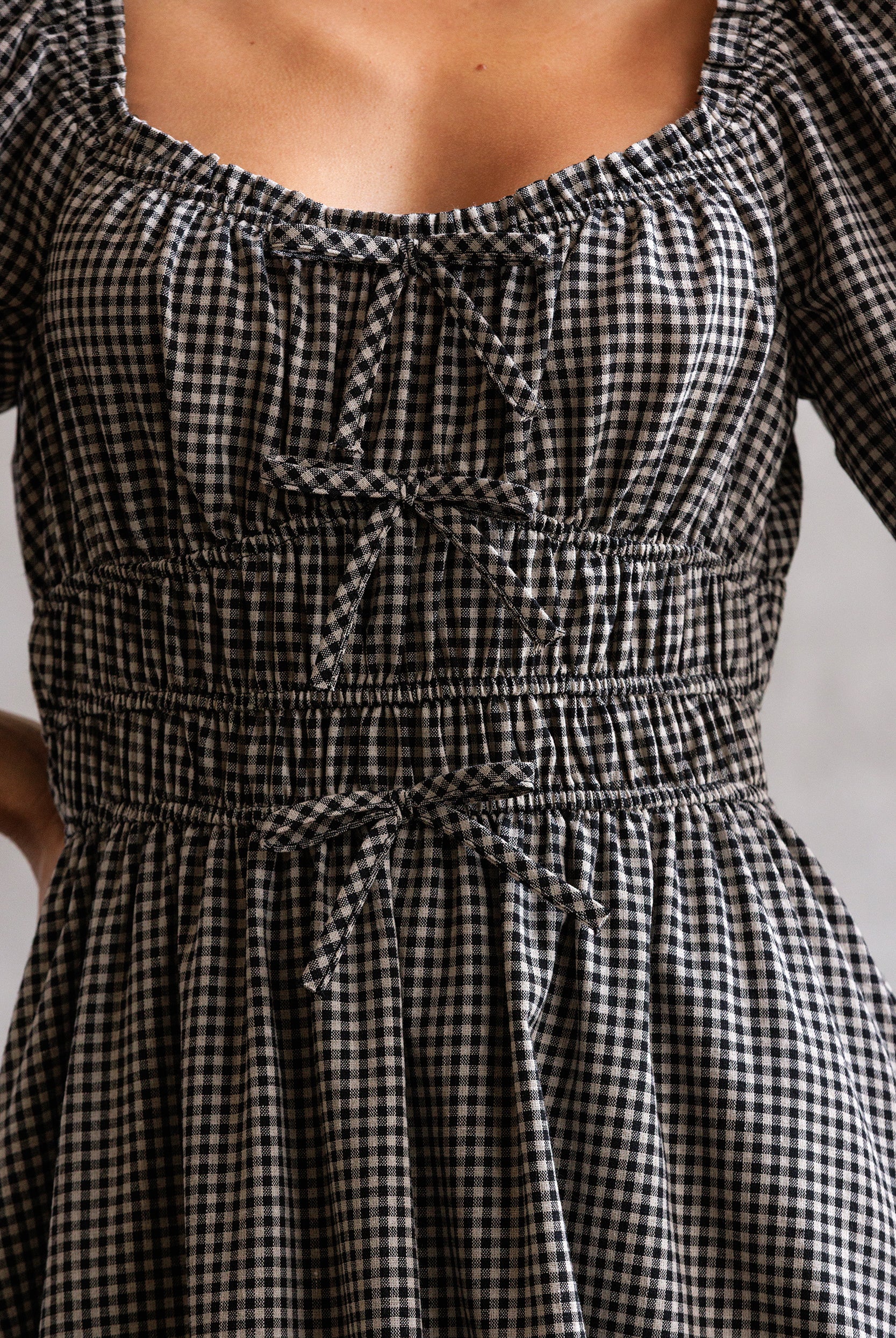 Black and white checkered dress with a tie waist on a neutral background