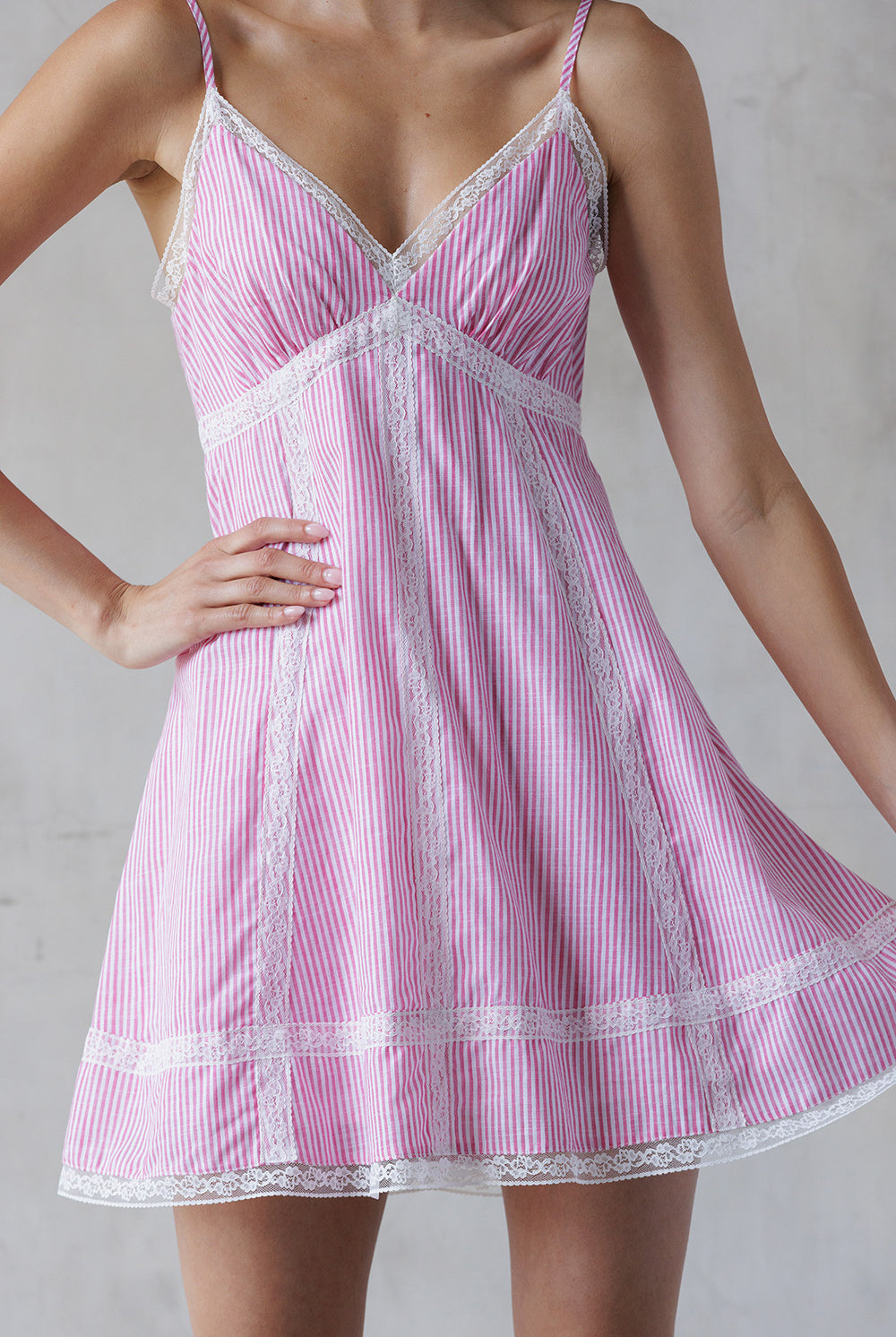 Pink and white striped dress with lace trim on a plain background
