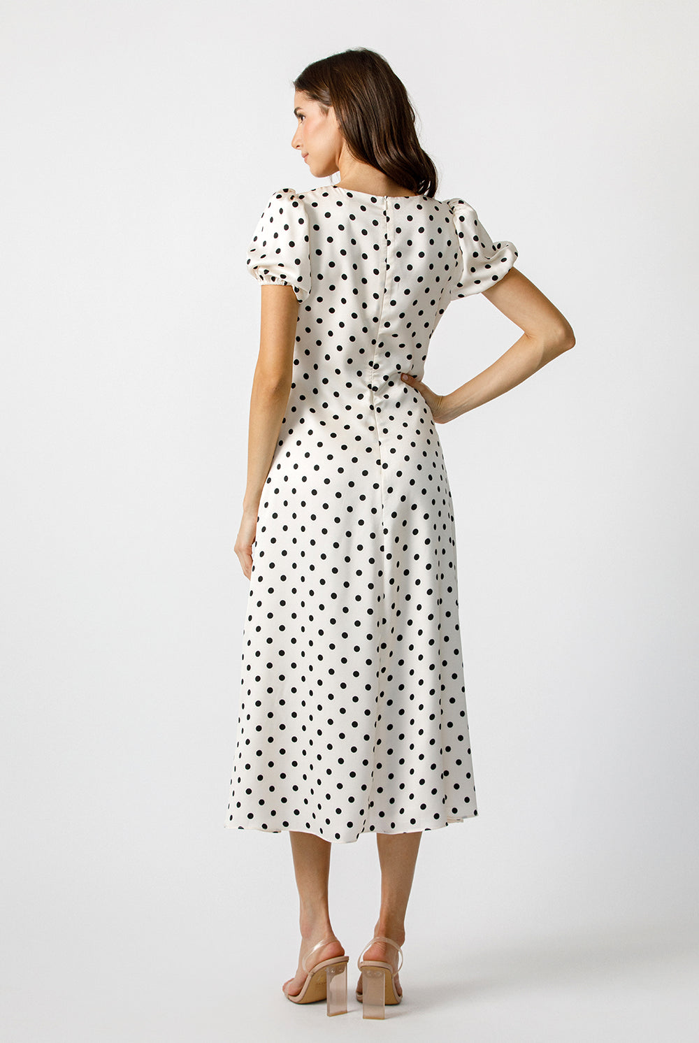 Back view of a woman wearing a polka dot dress on a white background