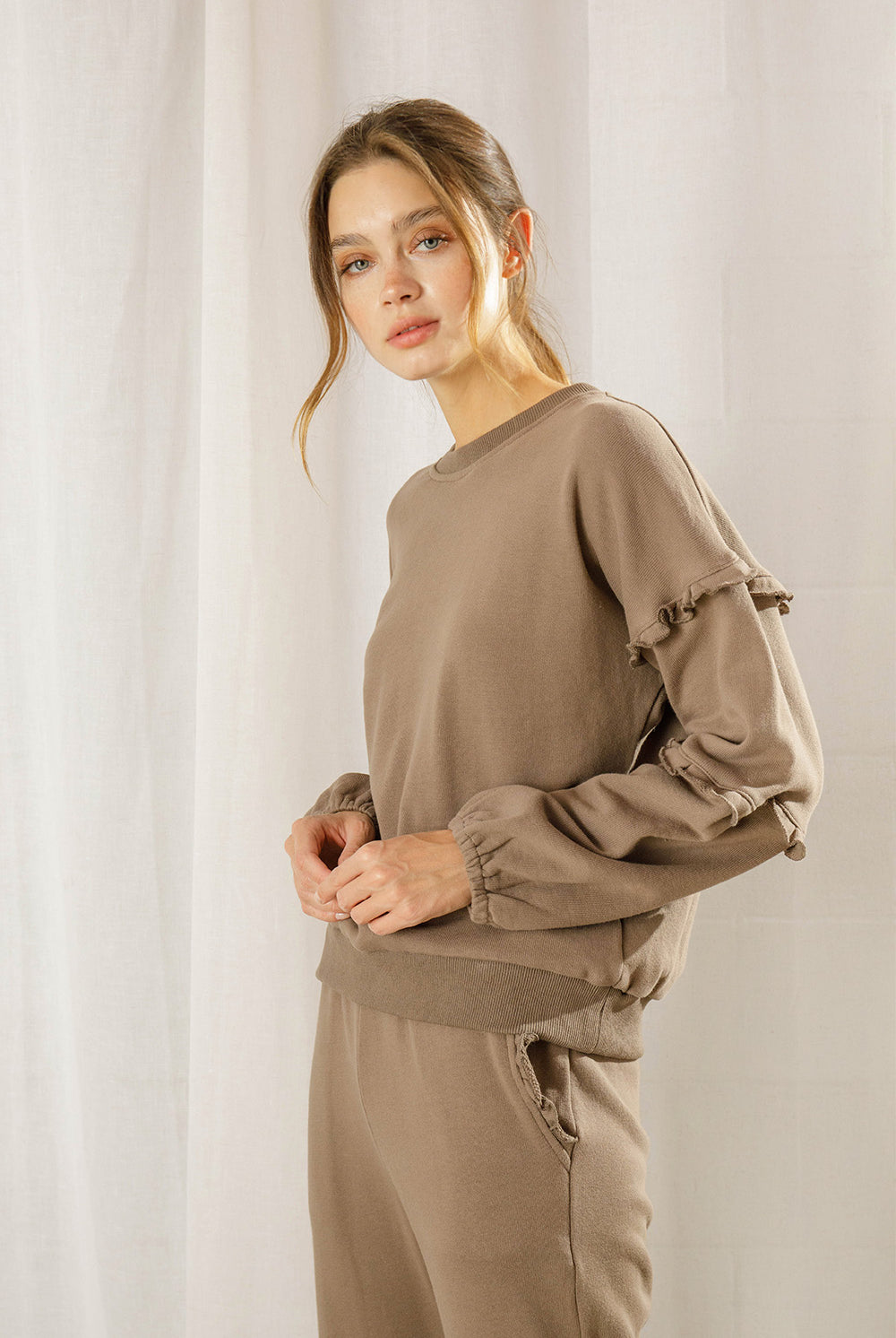 Woman wearing a brown outfit against a plain background