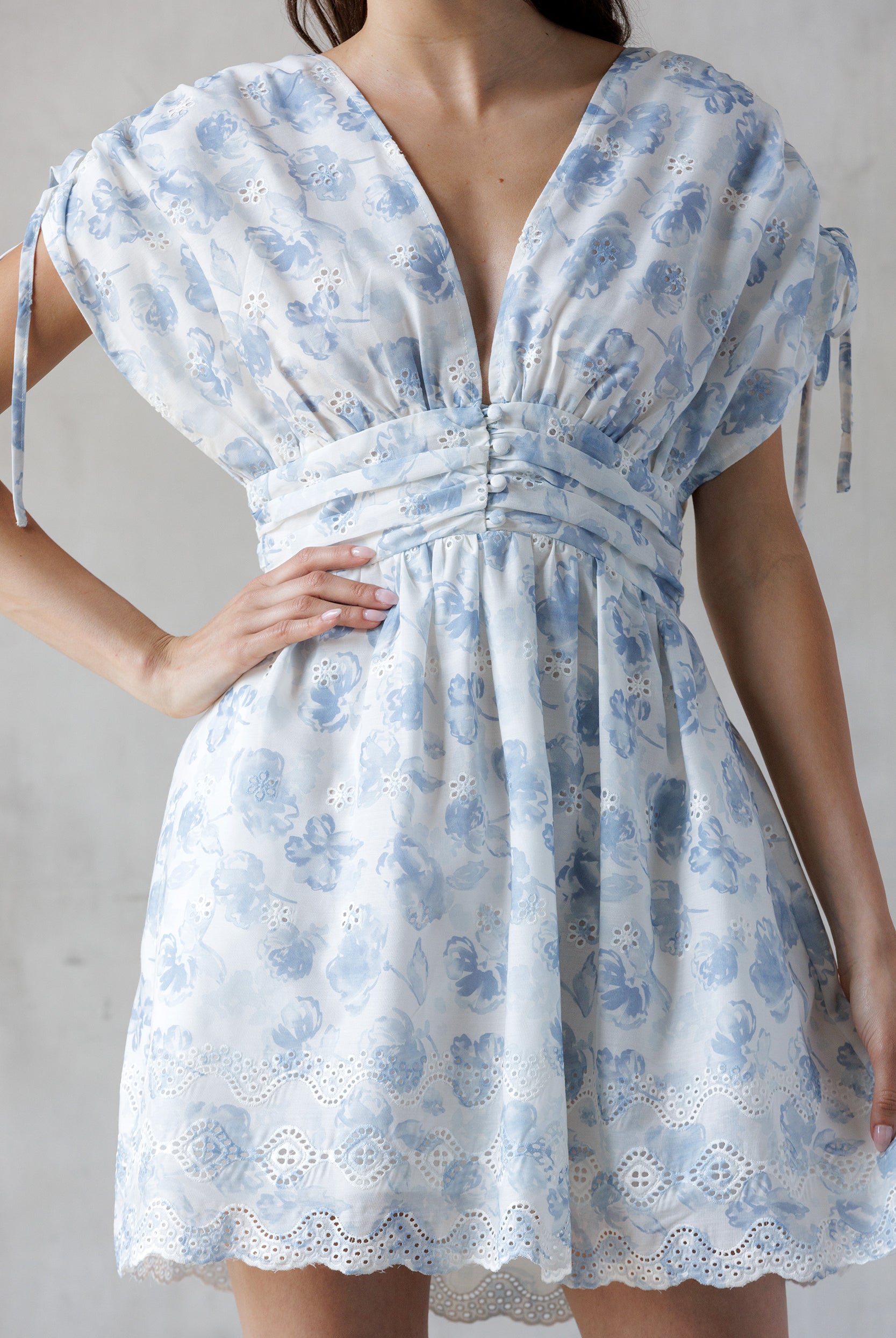 Blue and white dress with blue floral pattern worn by a person on a plain background