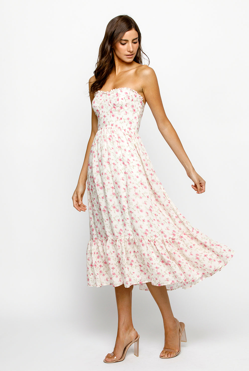 Side view of a woman wearing a strapless cream floral dress on a white background