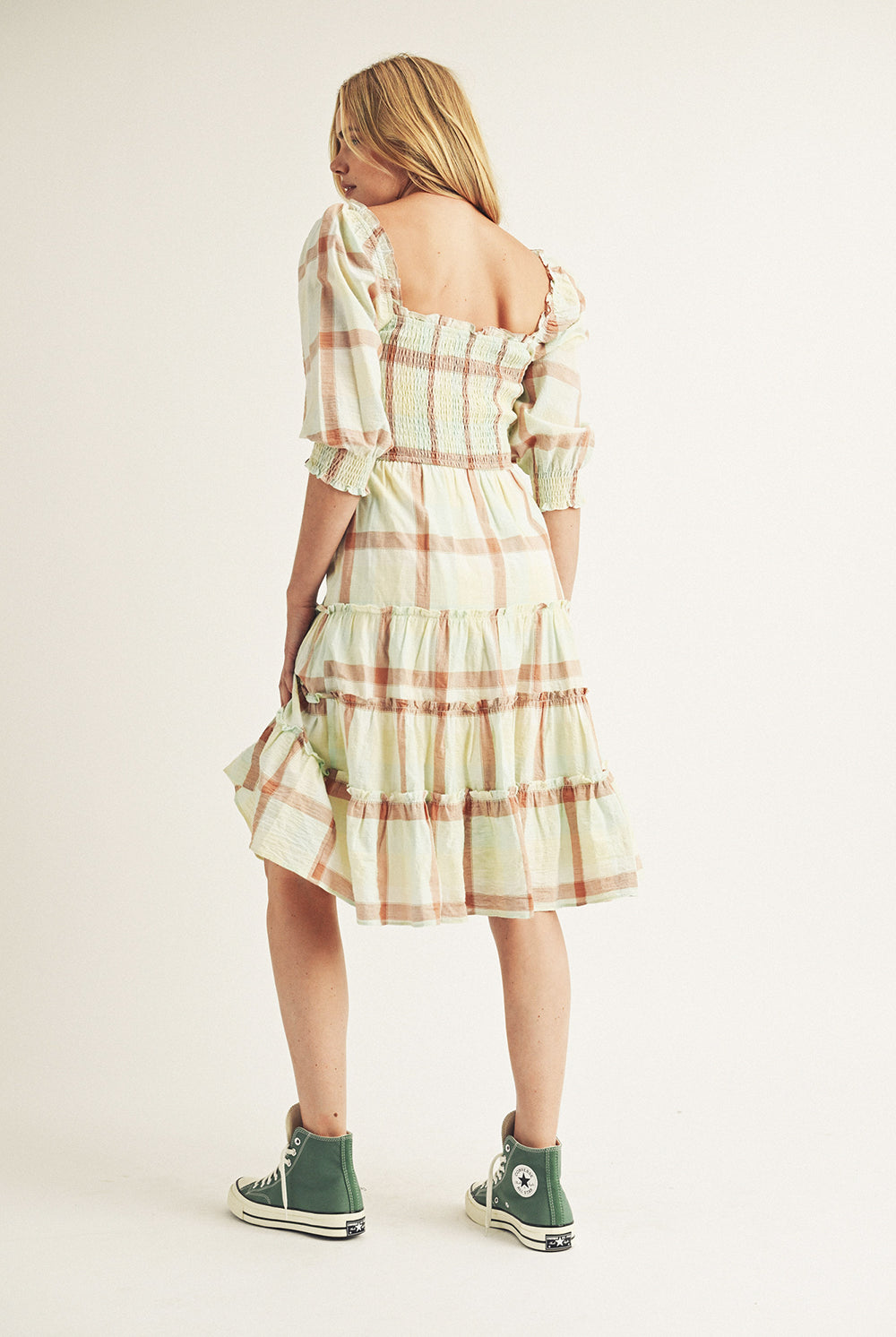 Woman wearing a plaid dress with a neutral background