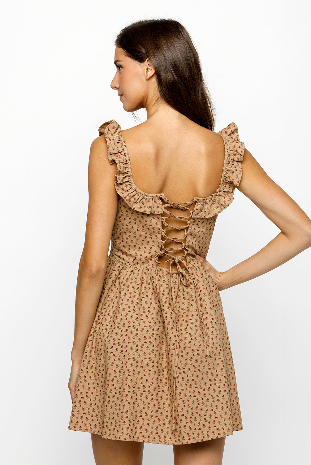 Woman wearing a brown and red floral dress with ruffled straps on a white background