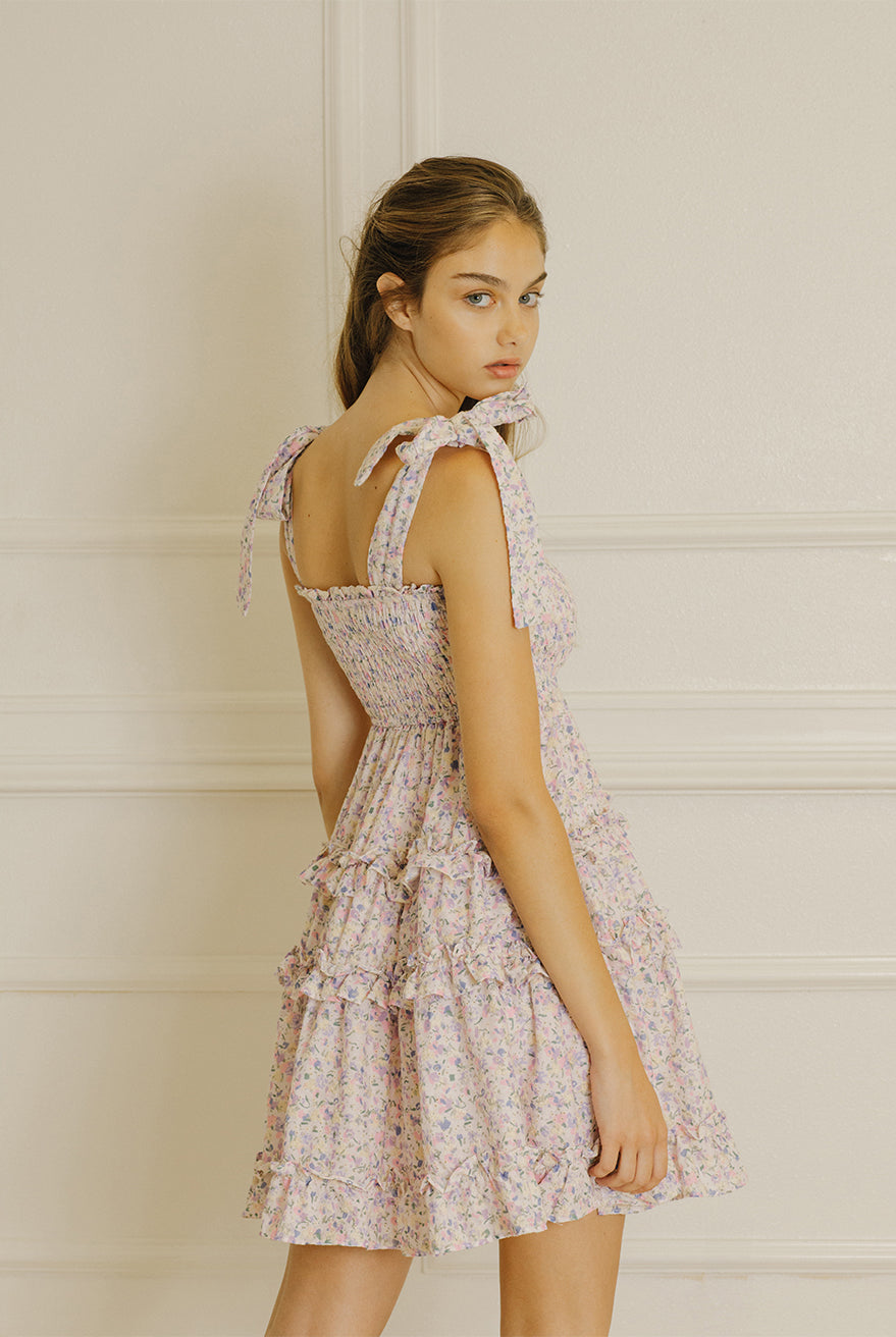 Back view of a woman wearing a floral dress with a white wall background