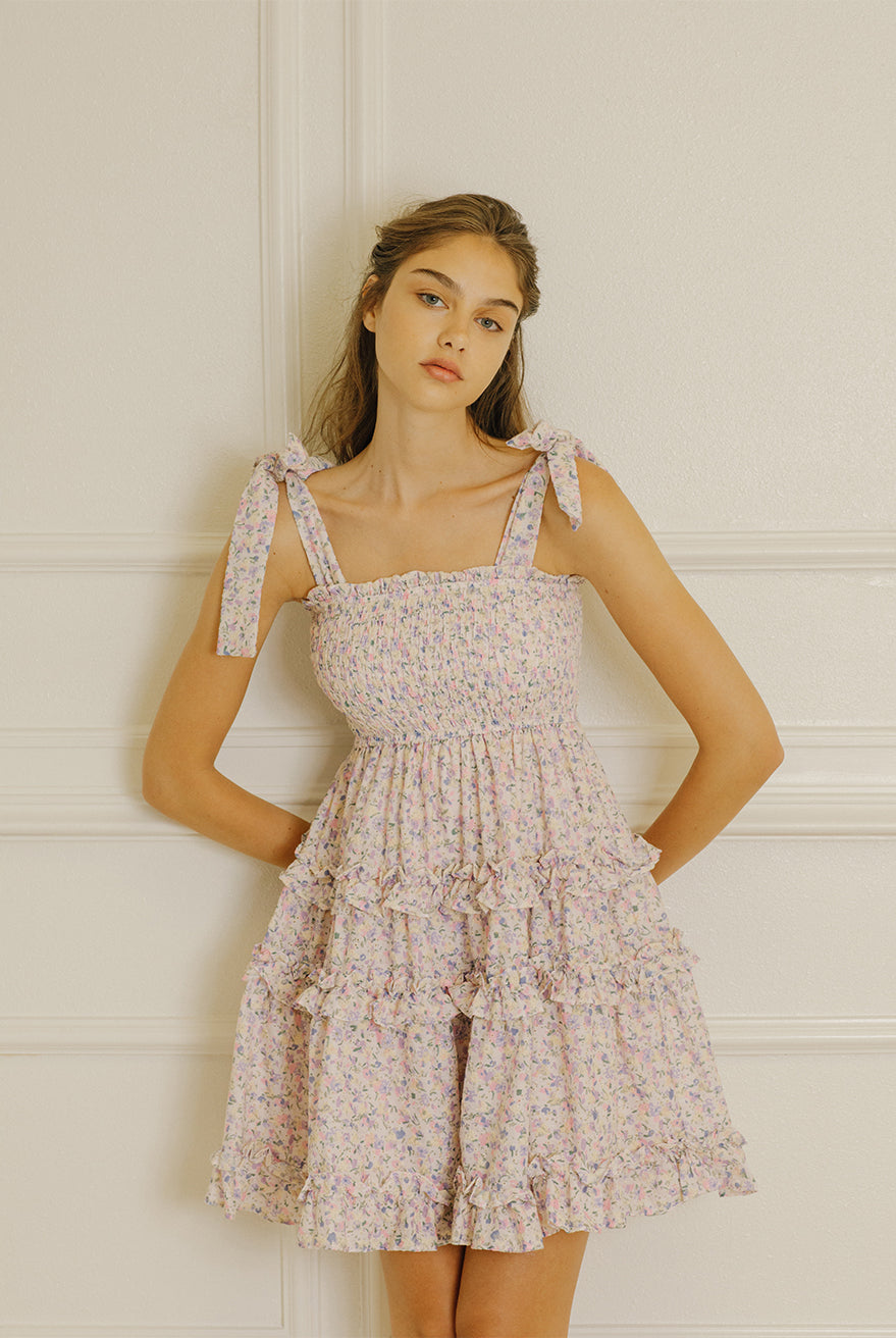 Woman wearing a floral dress against a light-colored wall