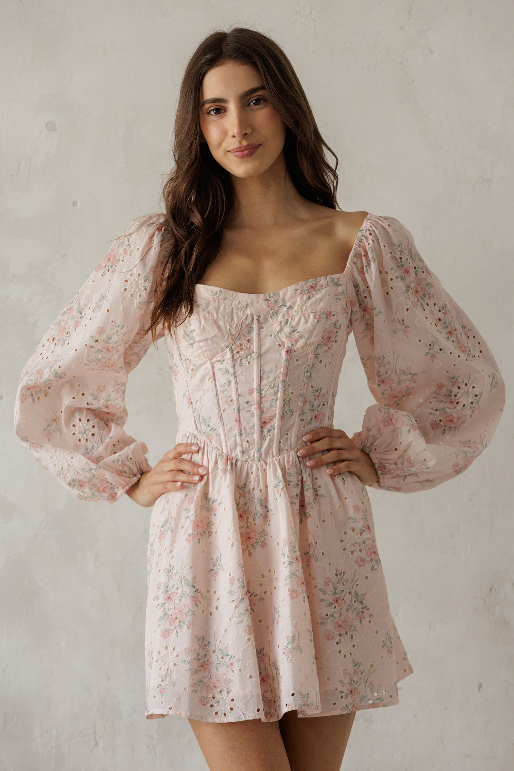 Woman wearing a light pink floral dress against a plain background