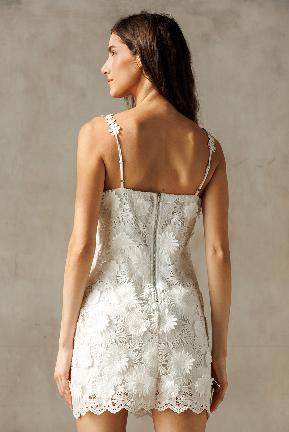 Woman wearing a white lace dress against a neutral background