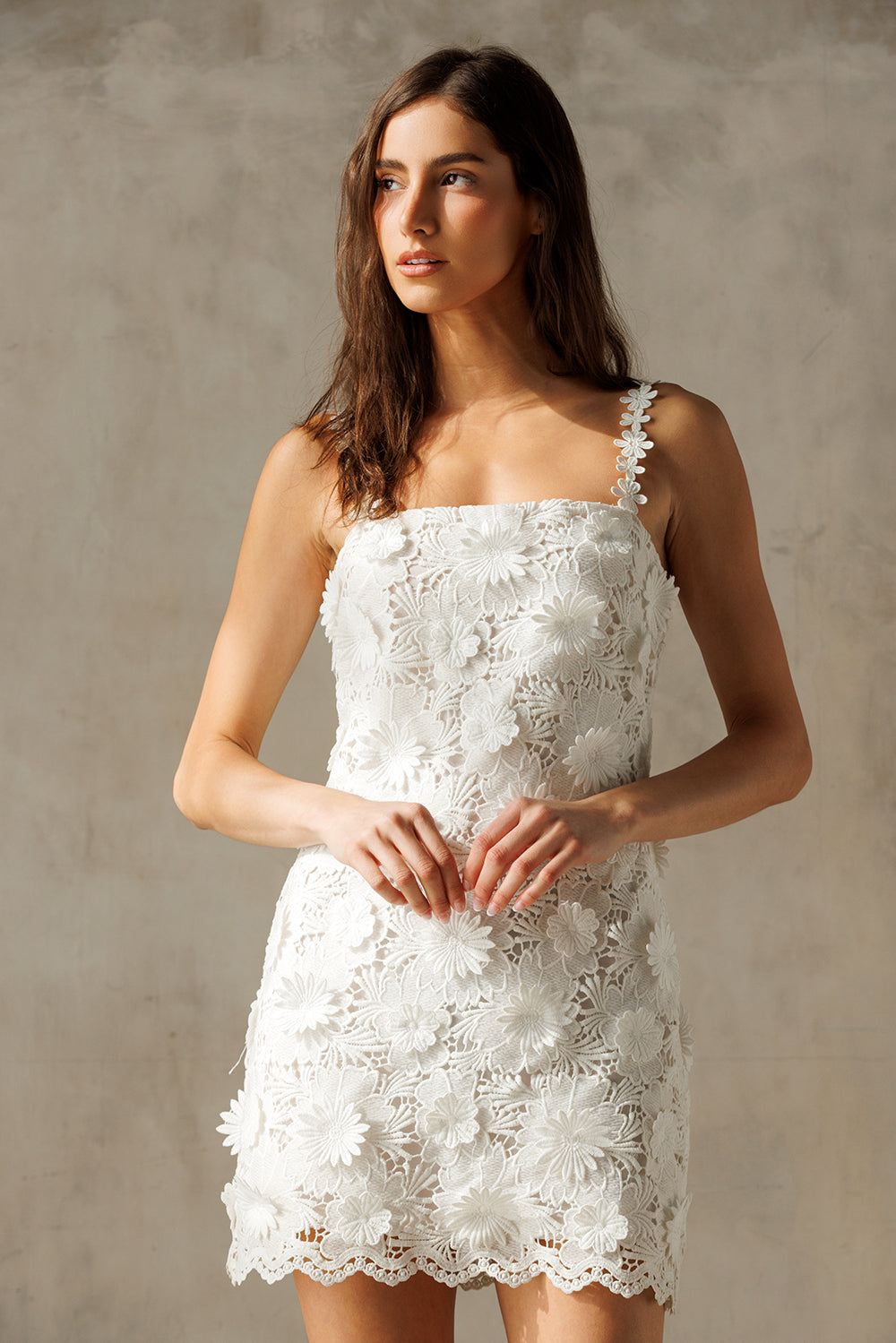 Woman wearing a white lace mini dress against a neutral background