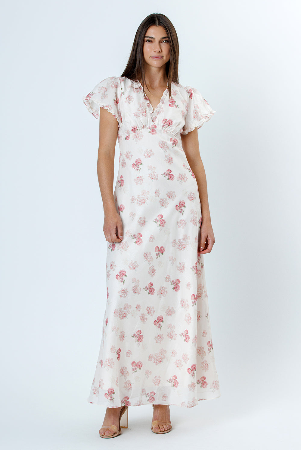 Woman wearing a white floral dress with flutter sleeves on a white background