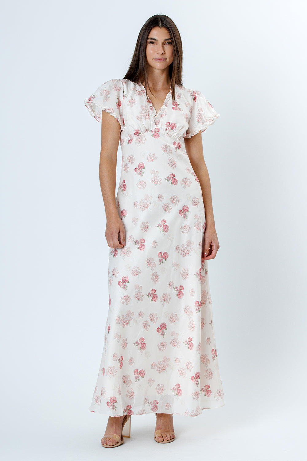 Woman wearing a white floral dress with flutter sleeves on a white background