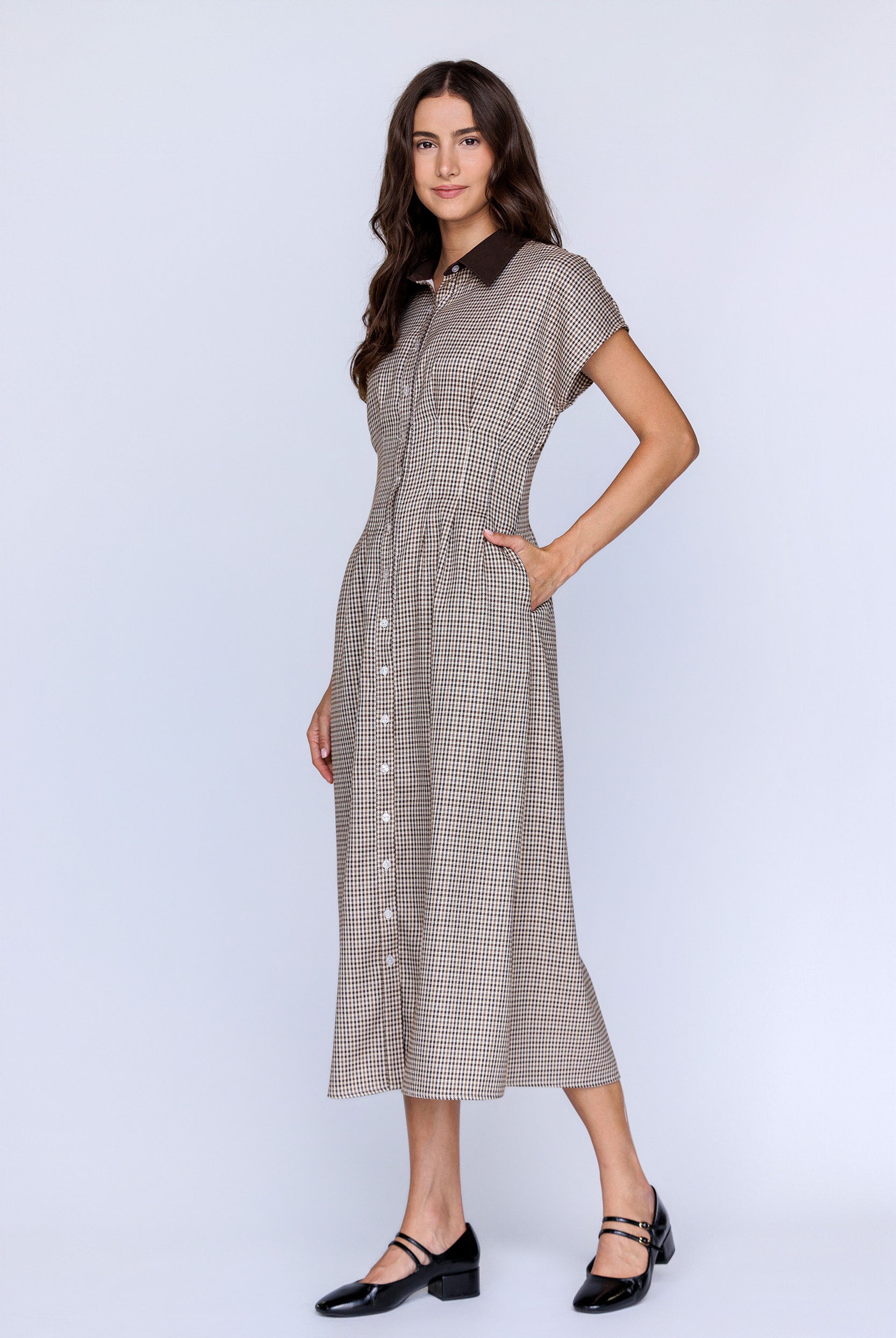 Side view of a woman wearing a checkered dress on a white background