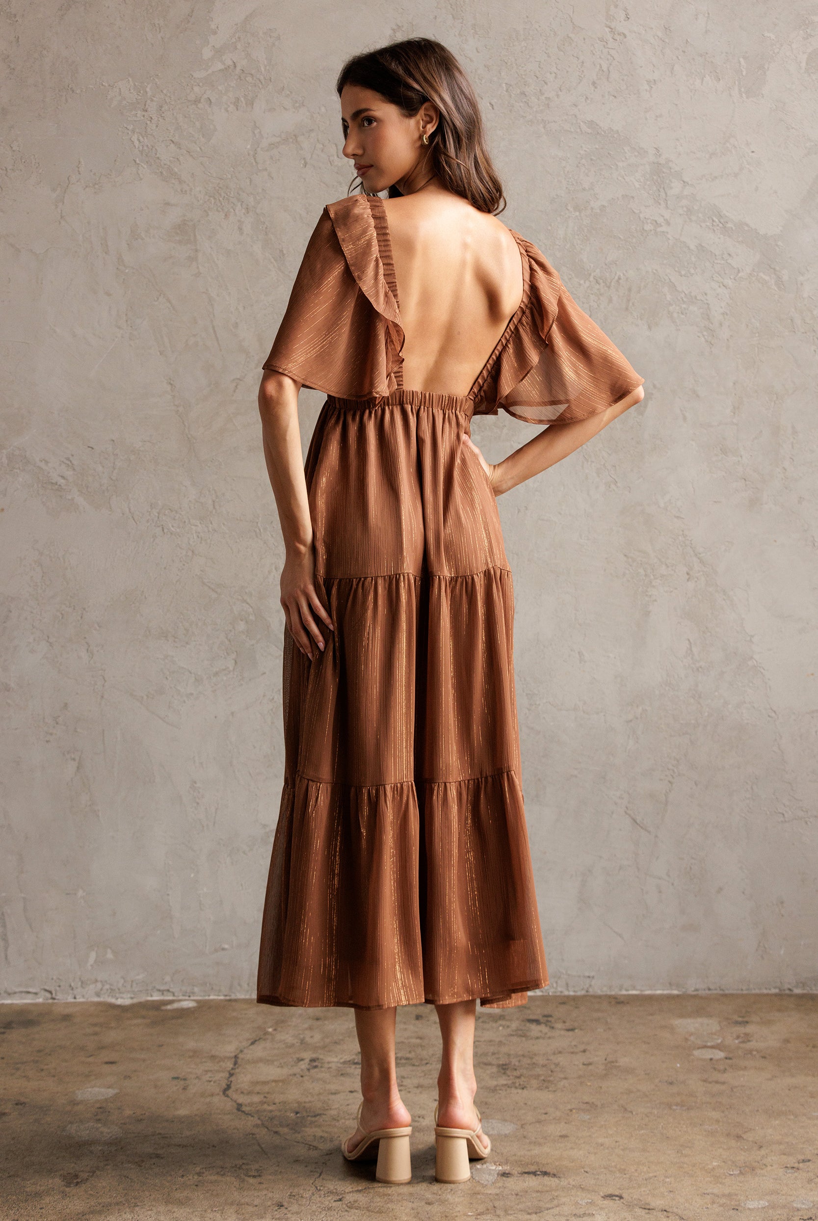 Woman wearing a brown dress against a plain wall