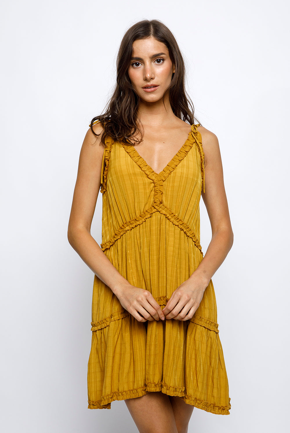 Woman wearing a mustard yellow dress against a white background