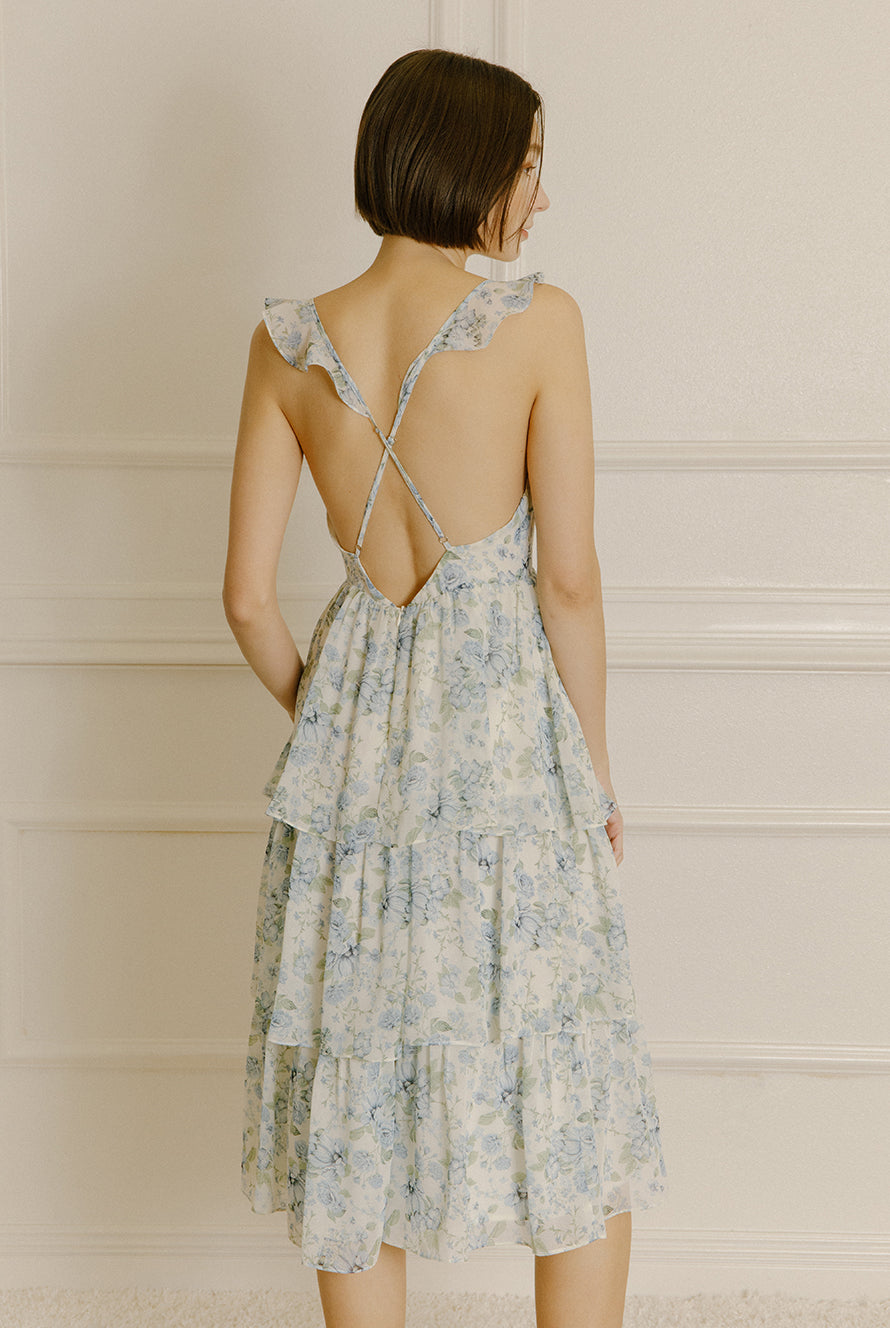 Back view of a woman wearing a blue floral midi dress with adjustable cross-back spaghetti straps