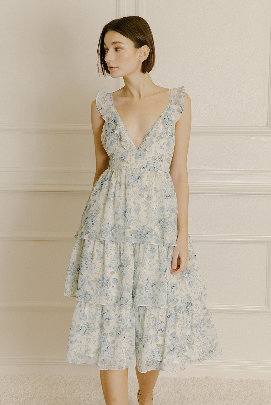 Woman wearing a blue floral midi dress with a ruffled tiered midi bottom