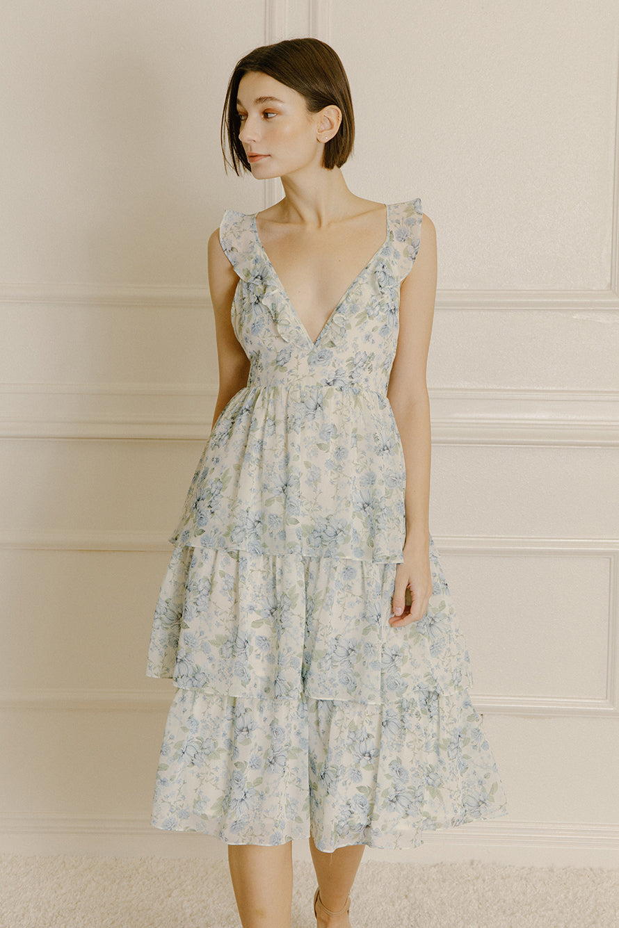 Woman wearing a blue floral midi dress with a ruffled tiered midi bottom