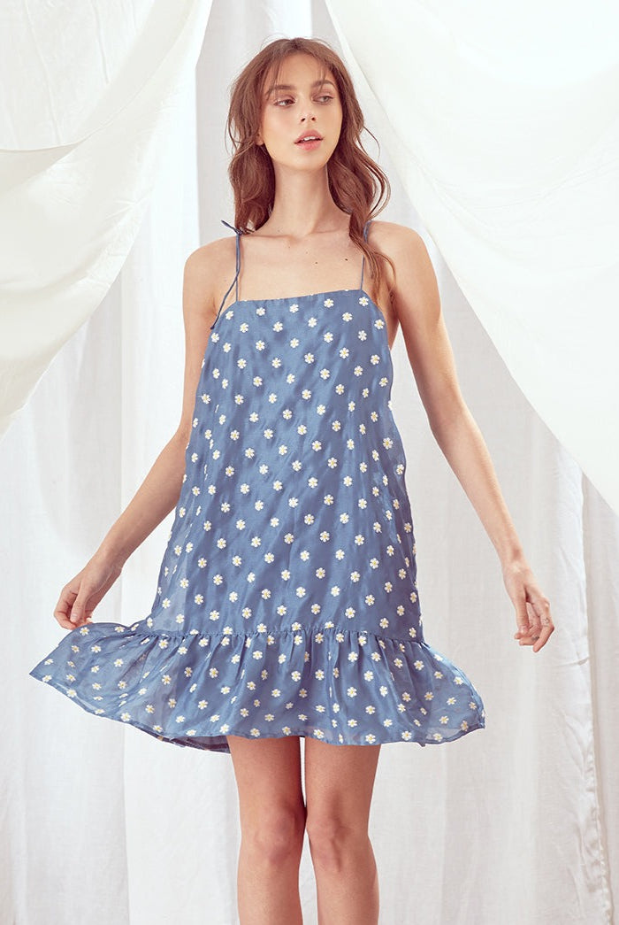 Woman wearing a blue floral dress against a white background