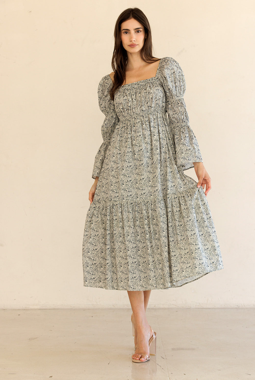 Woman wearing a floral midi dress with long sleeves against a plain background