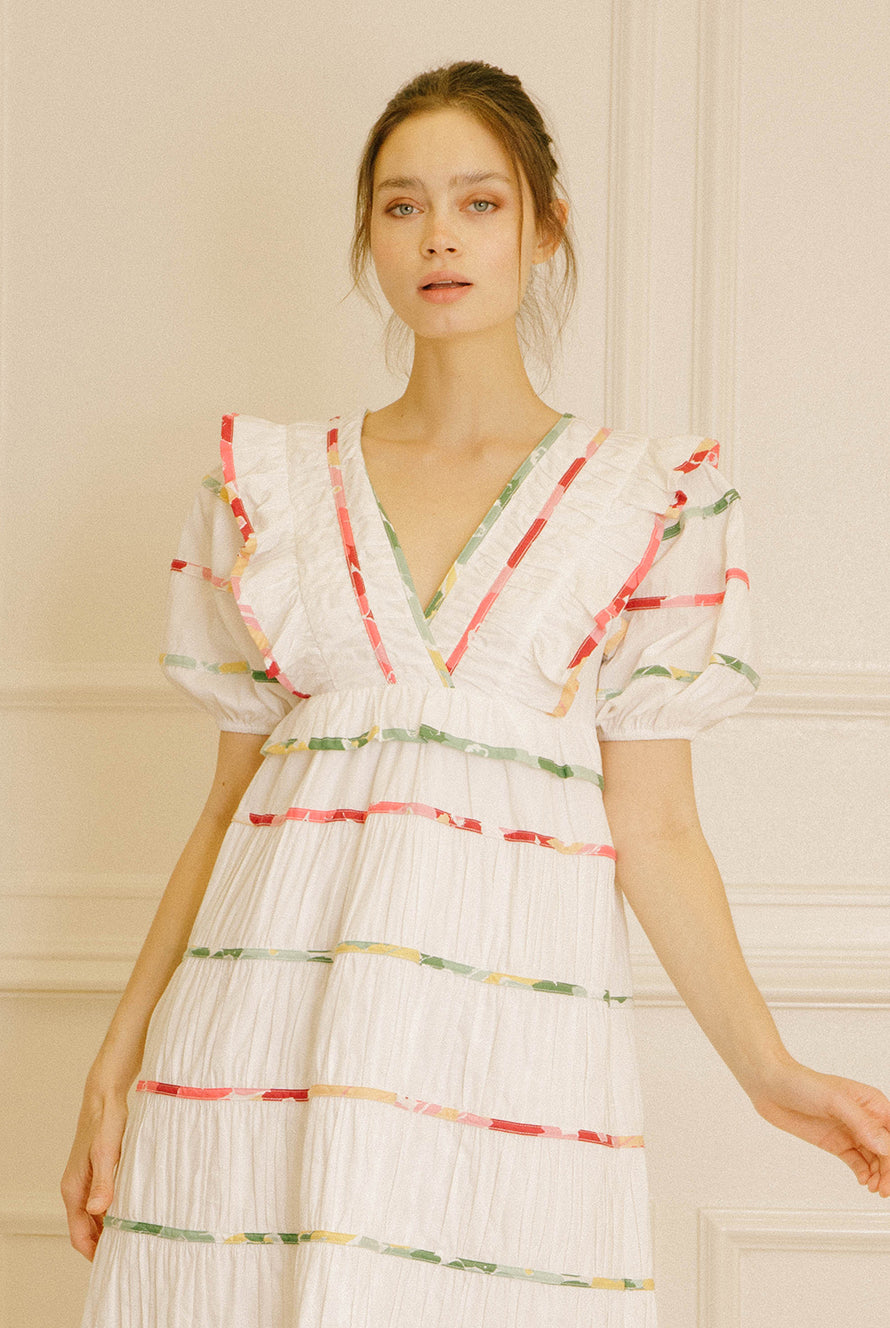 White dress with colorful stripes against a beige wall.