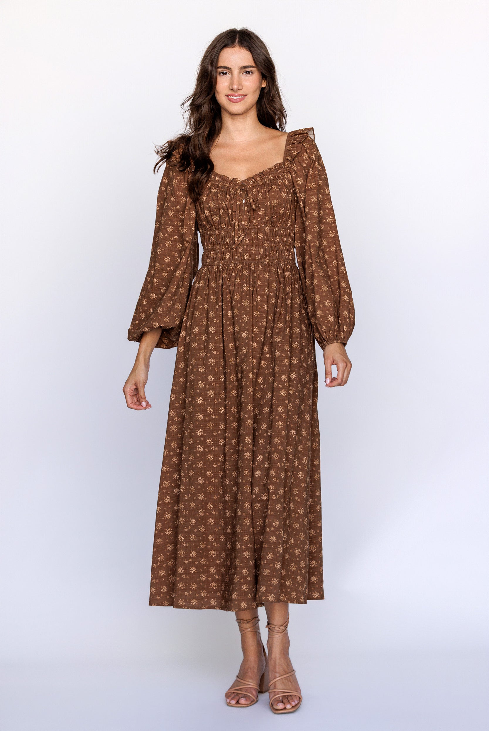 Woman wearing a brown patterned dress with long sleeves on a white background